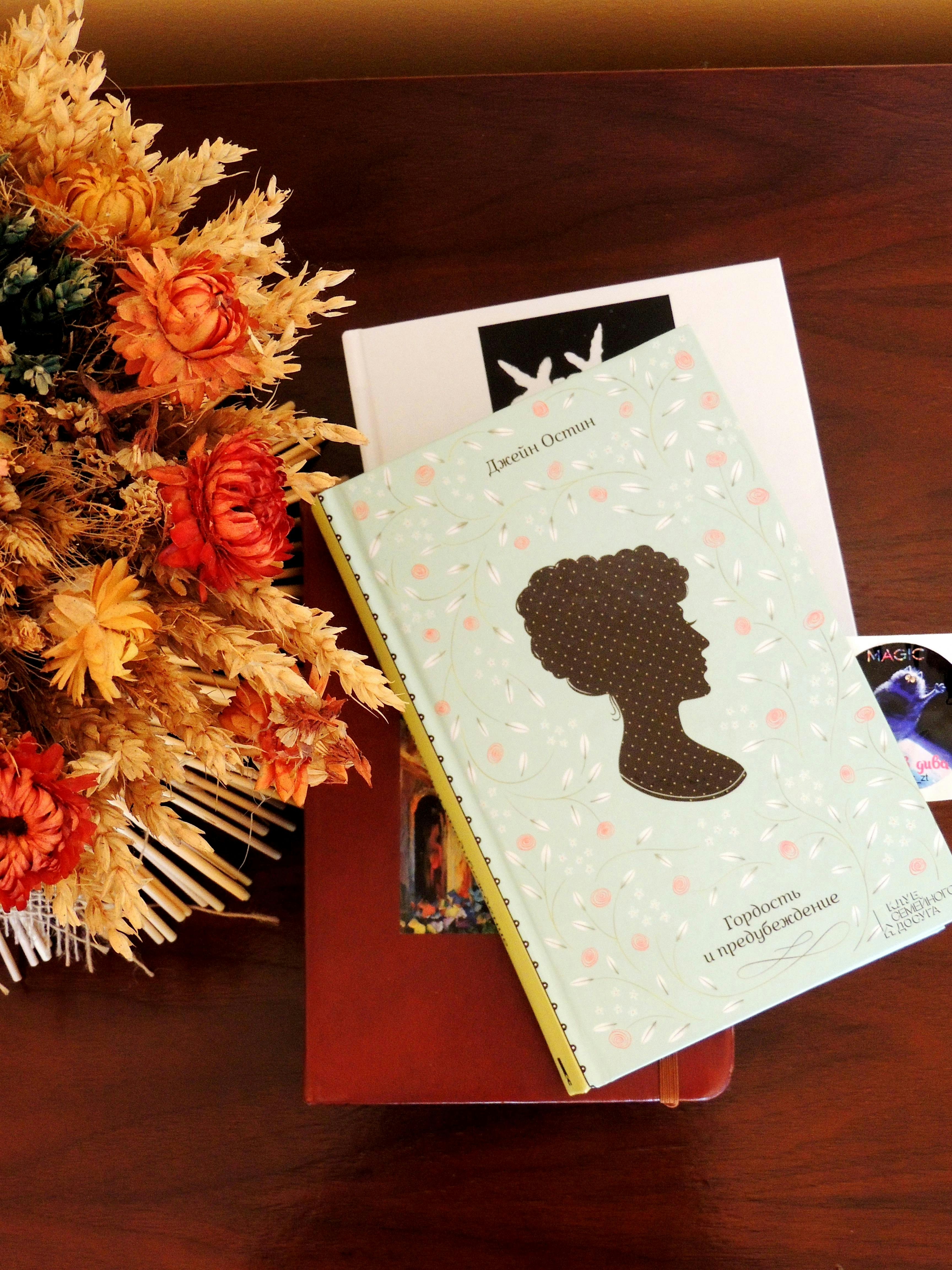 Books and dried flowers on a wooden surface.