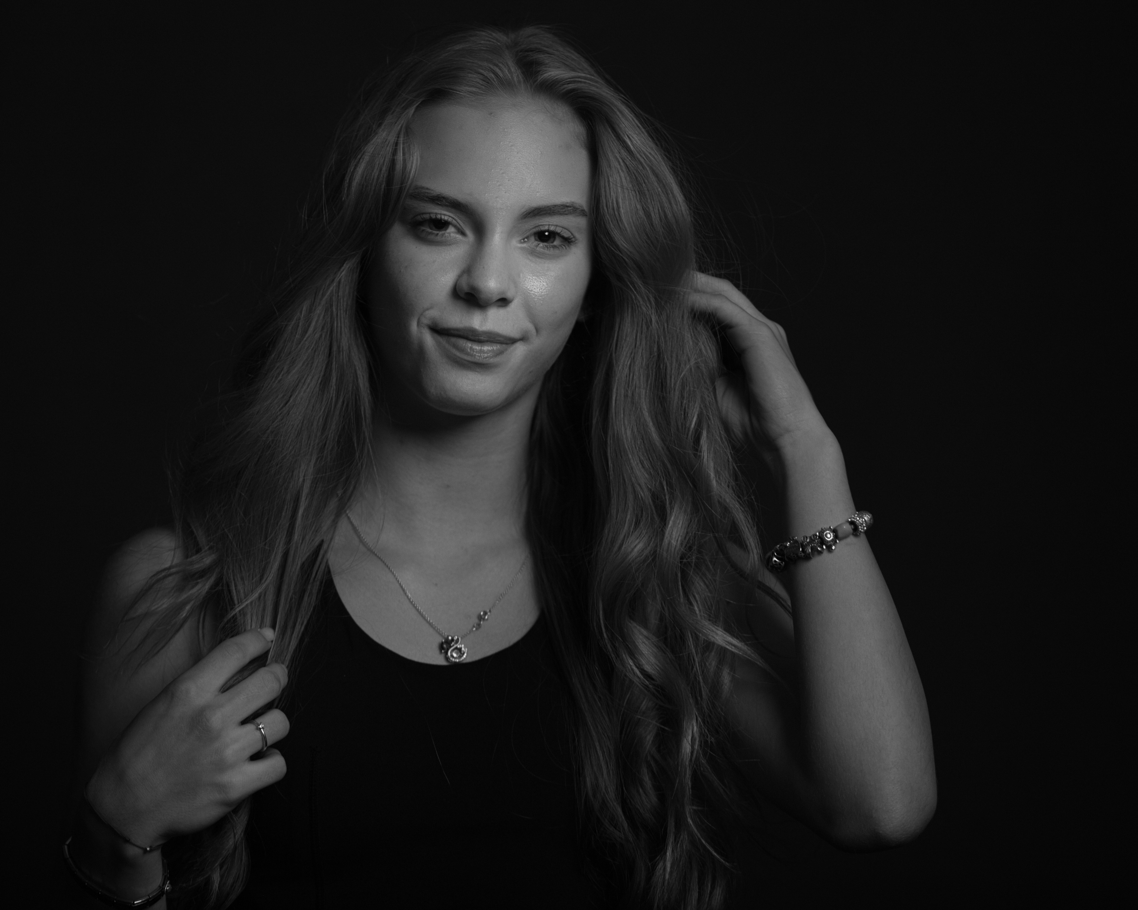 Young woman with long wavy hair and necklace.