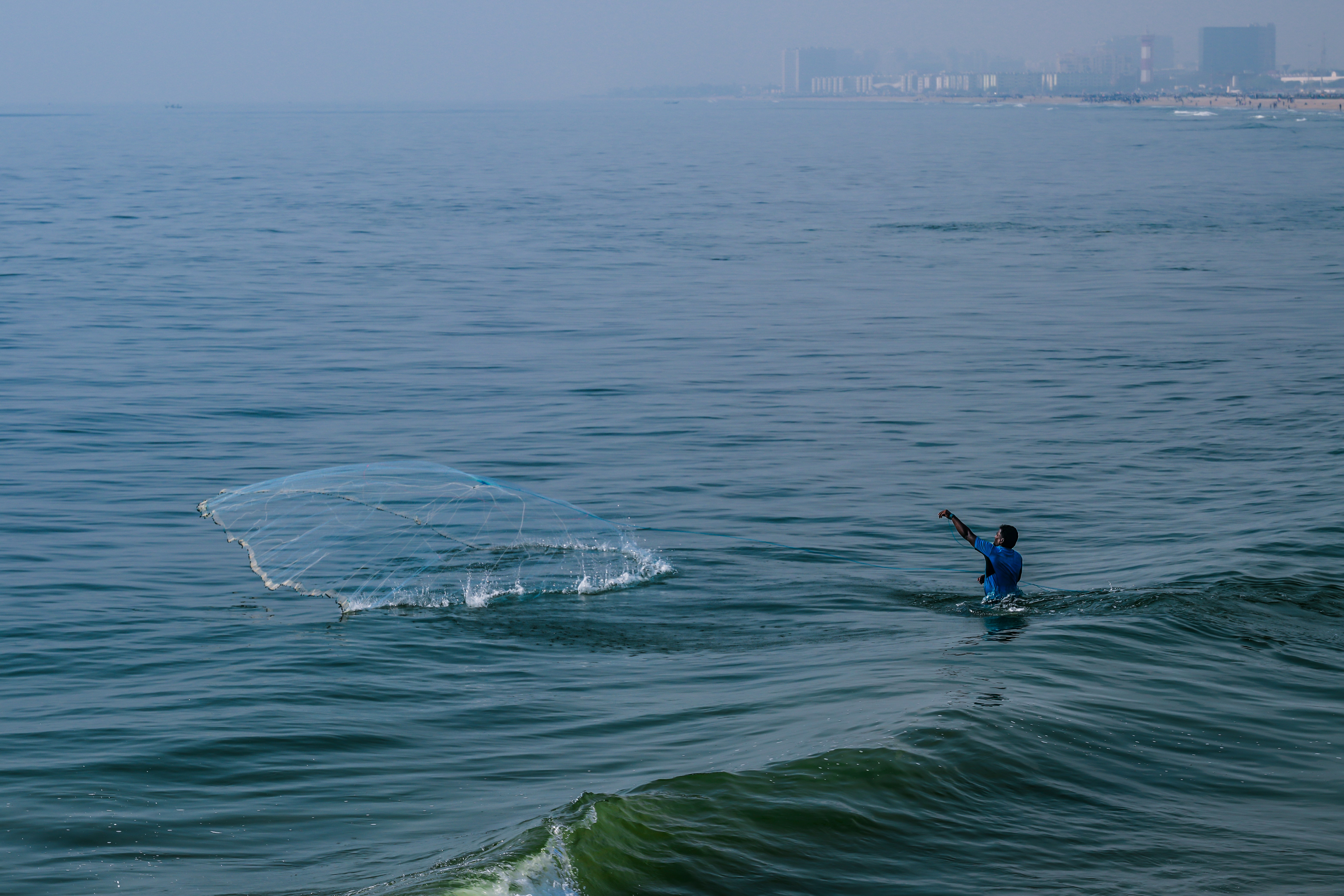 Fisherman casting net into the ocean water