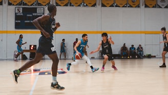 Basketball players dribbling and running on court.