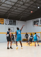 Basketball players practice shooting hoops in a gym.