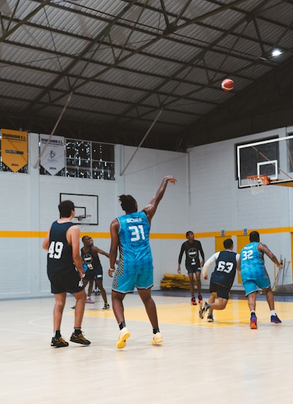 Basketball players practice shooting hoops in a gym.