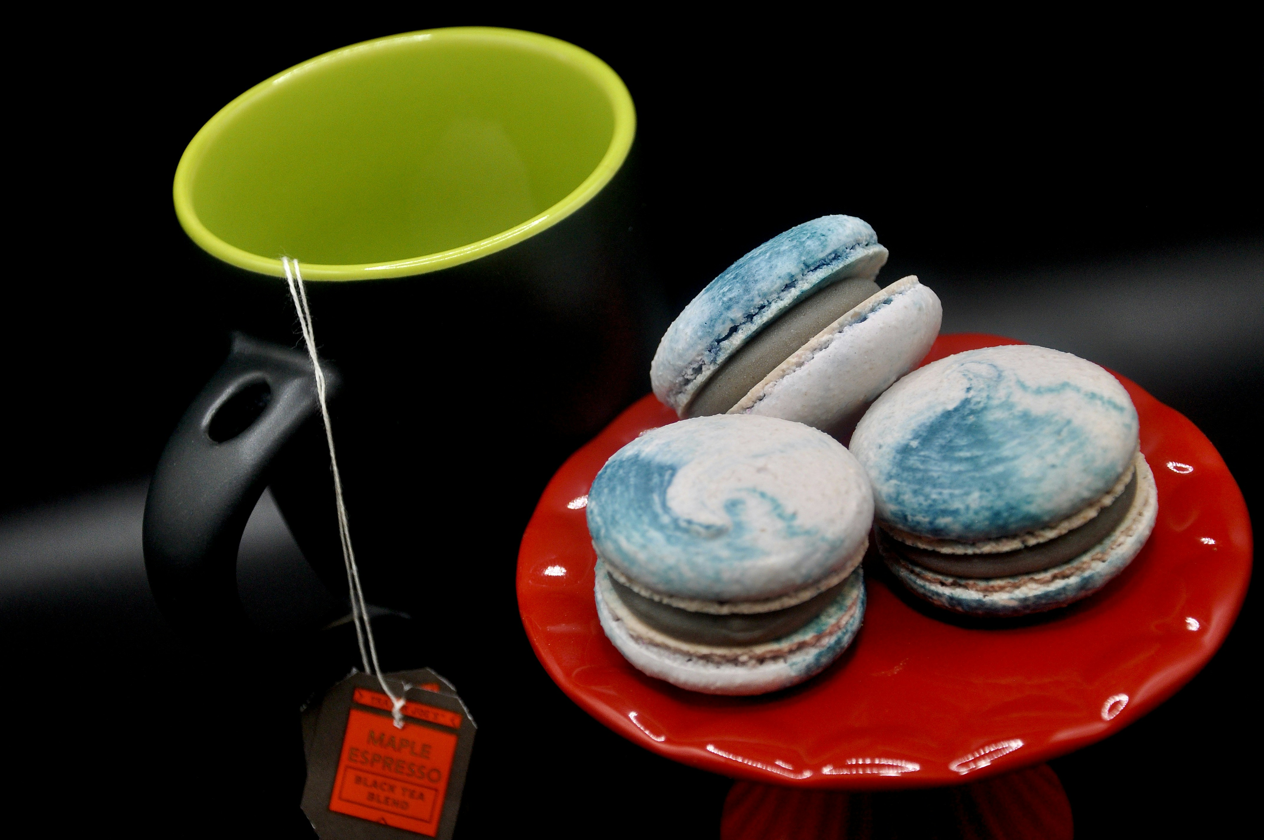 Three macarons on a red plate with green tag