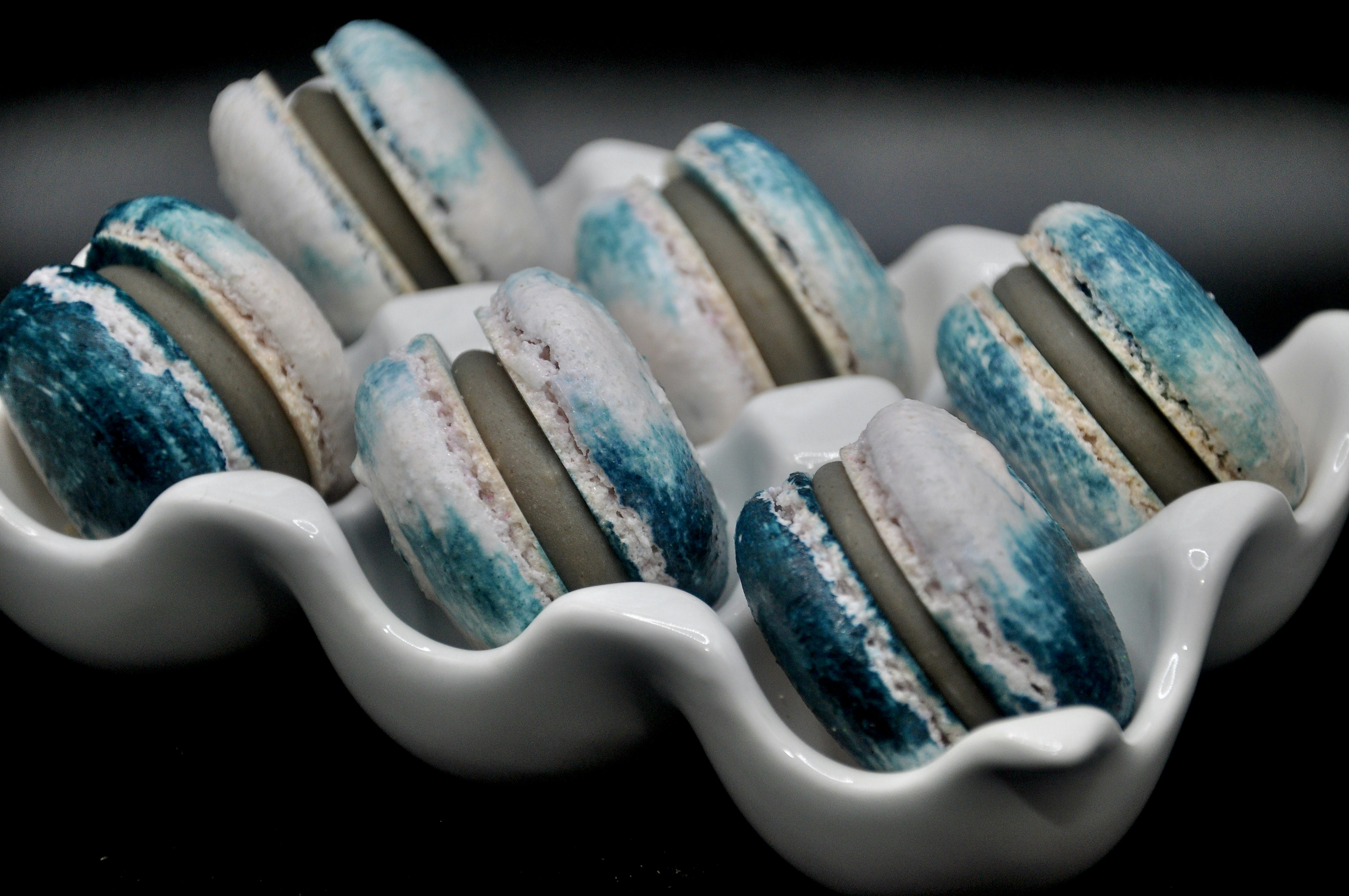 Six blue and white macarons in a white tray