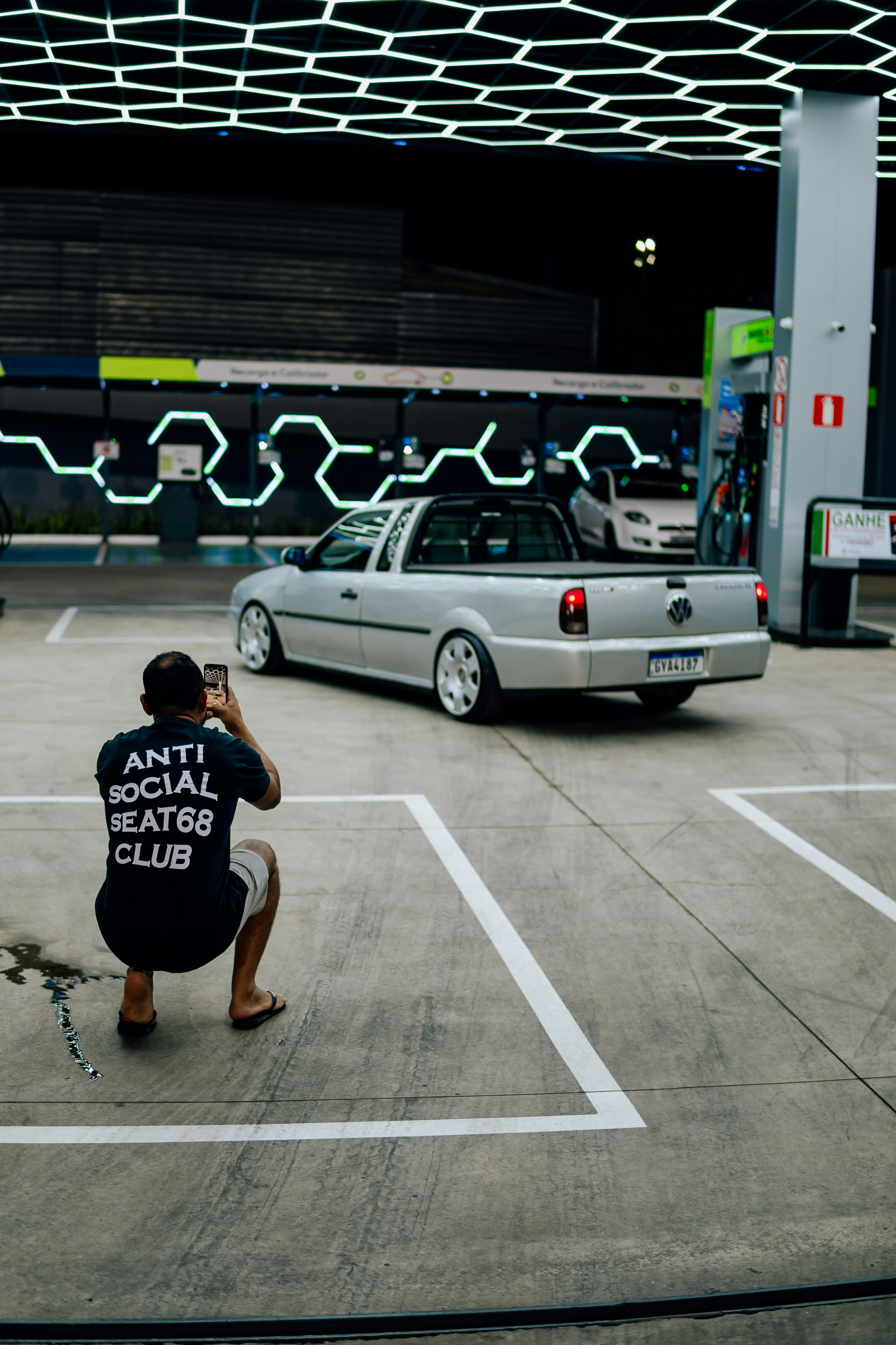 Man photographing a silver pickup truck at gas station