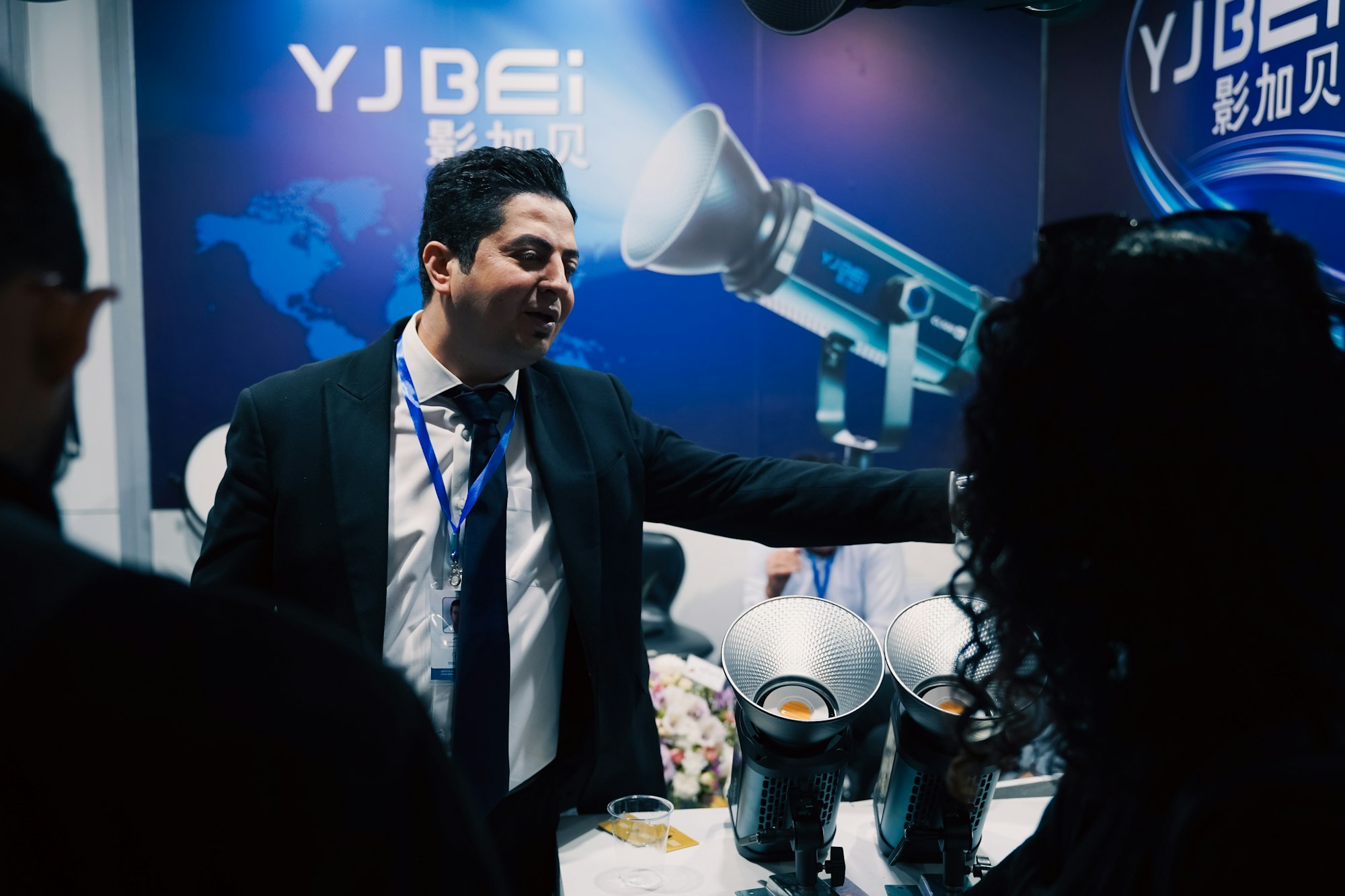 Man in suit presenting equipment at a professional trade show booth