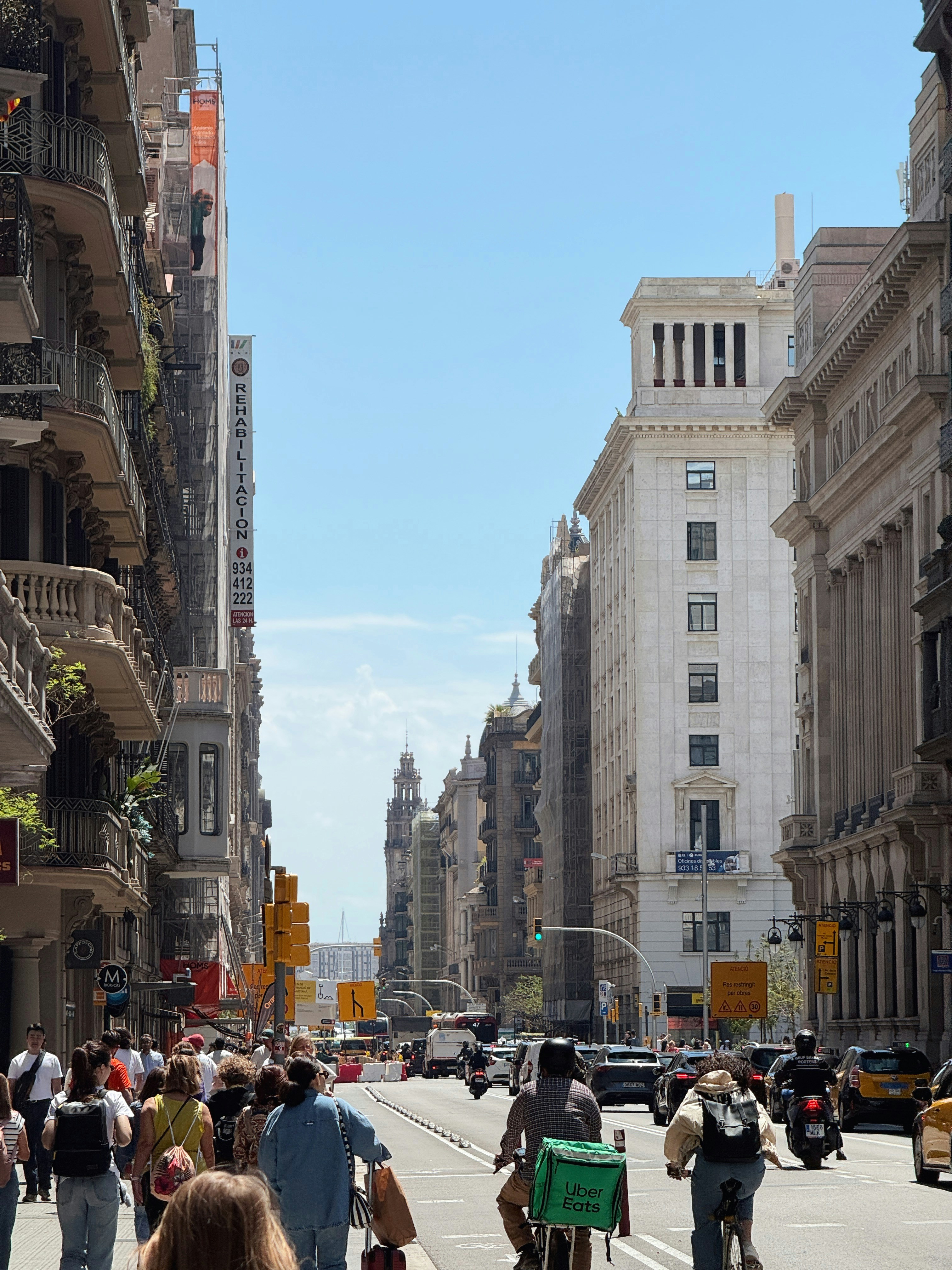 People walk and cycle down a sunny european city street.