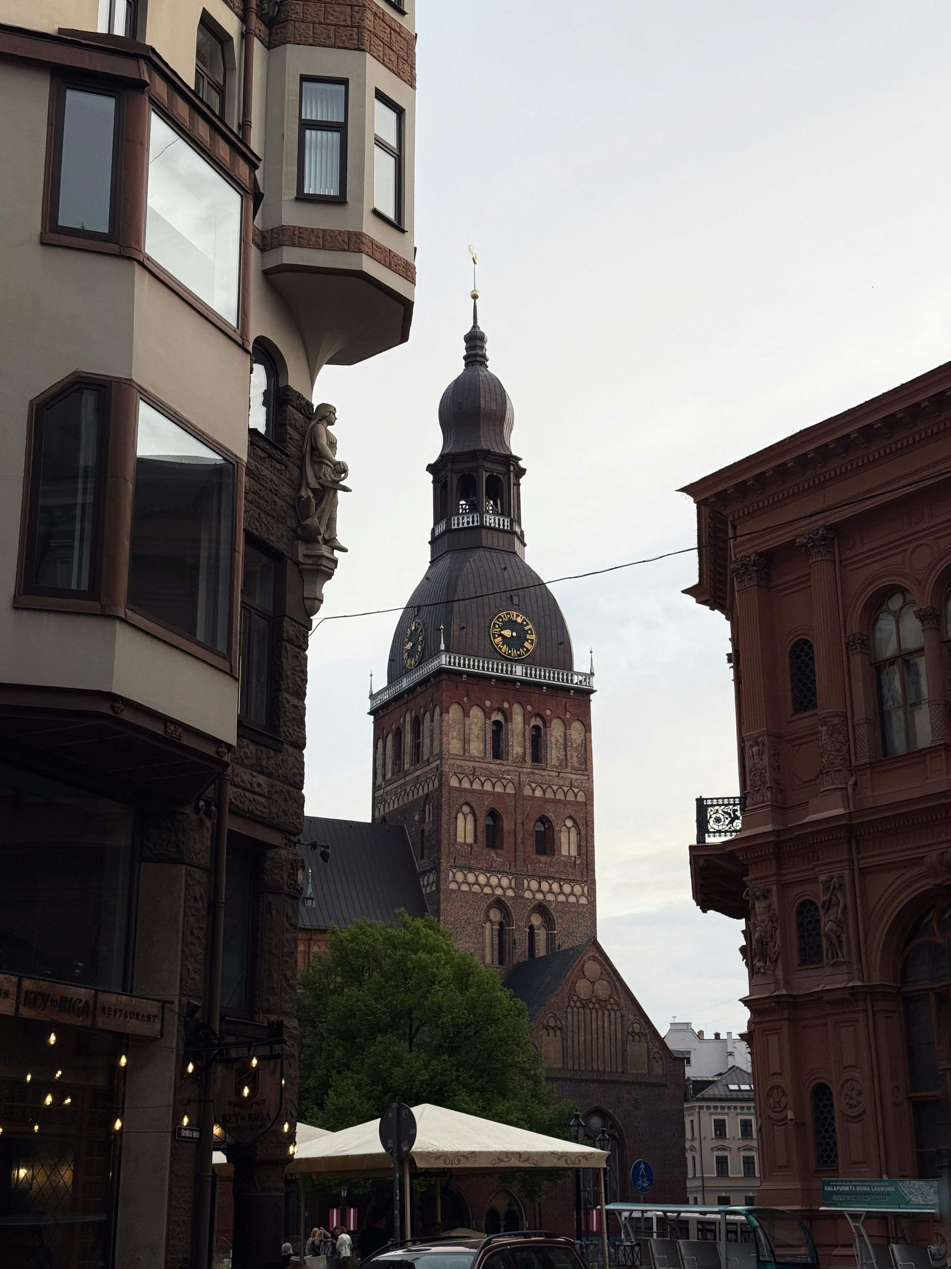 Tall brick church tower with clock face and spire.