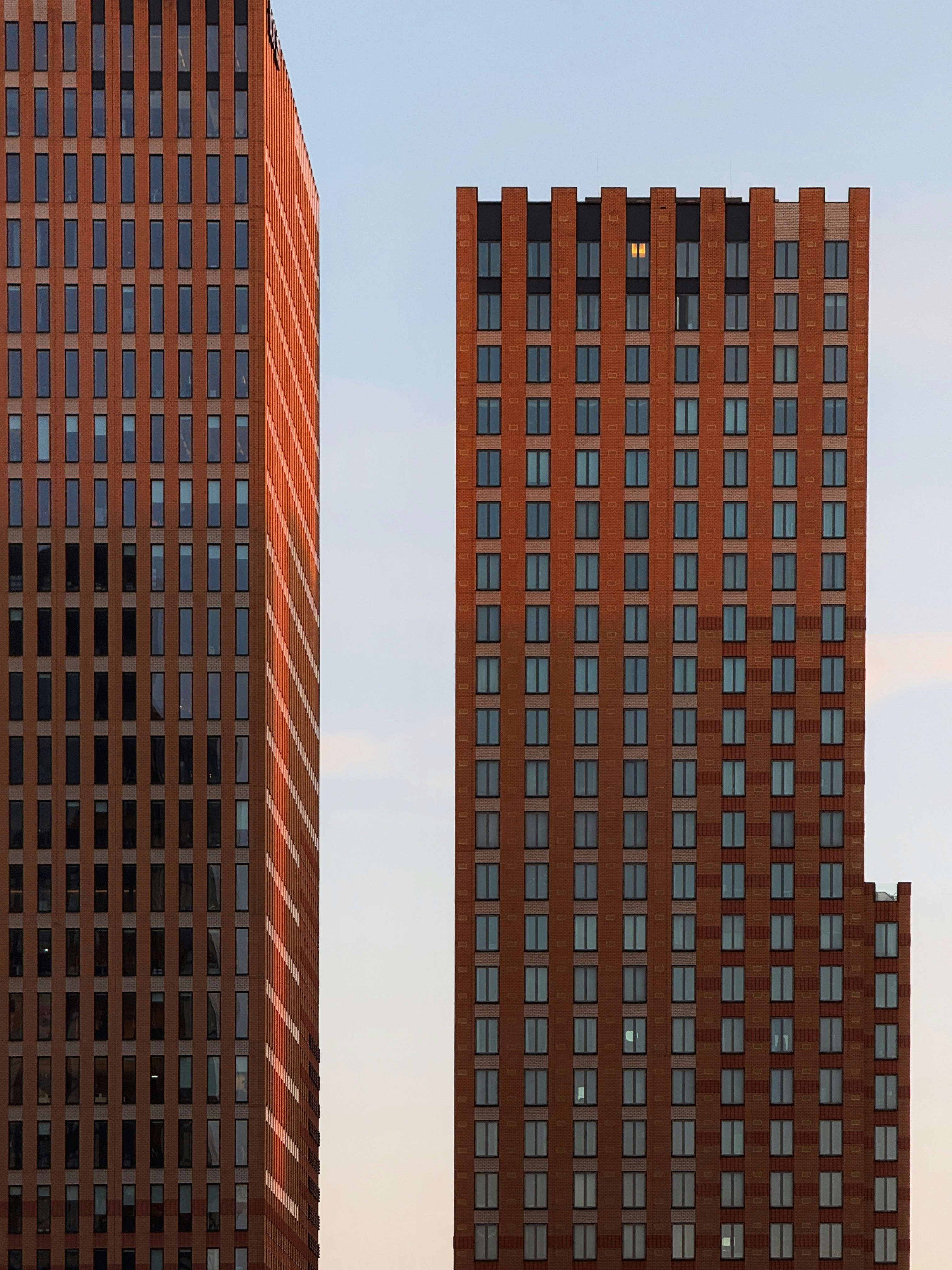 Two modern brick skyscrapers against a pale sky.
