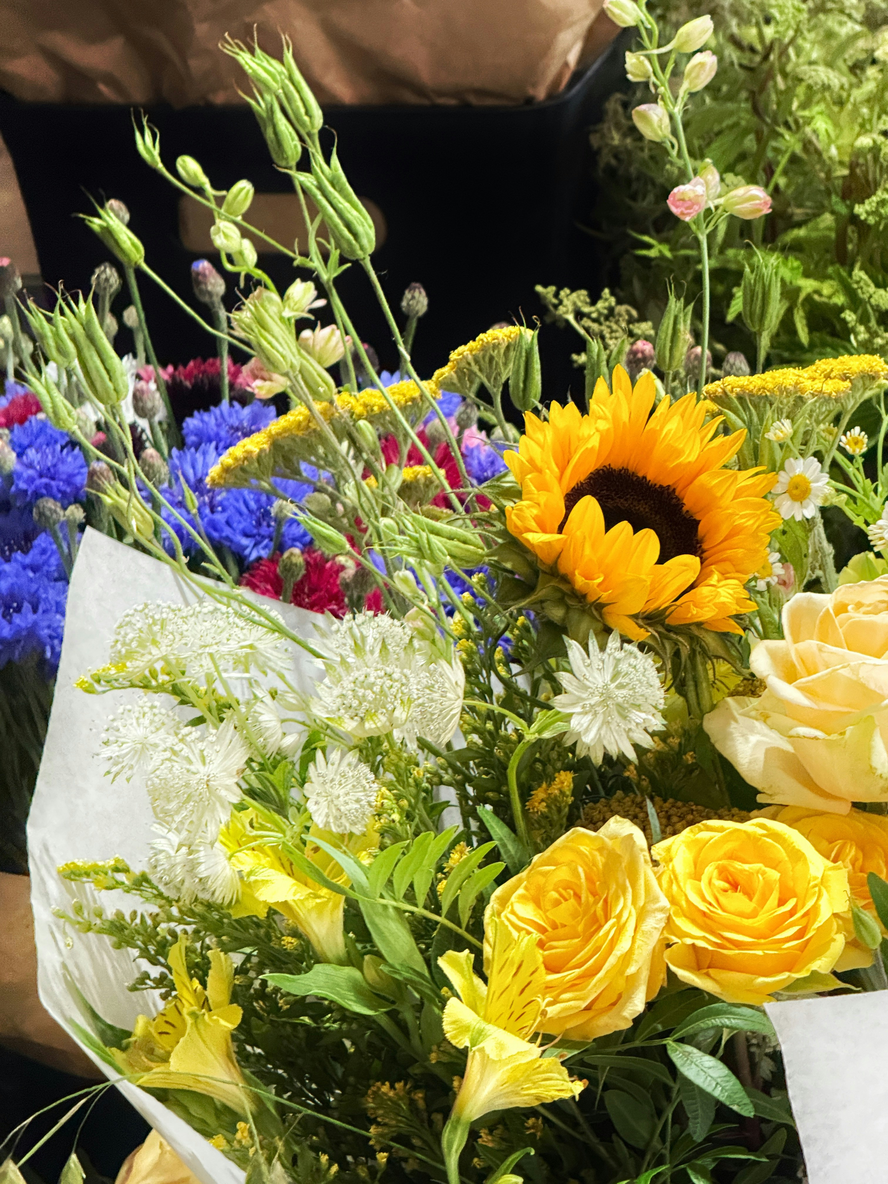 A vibrant bouquet of sunflowers, roses, and wildflowers.