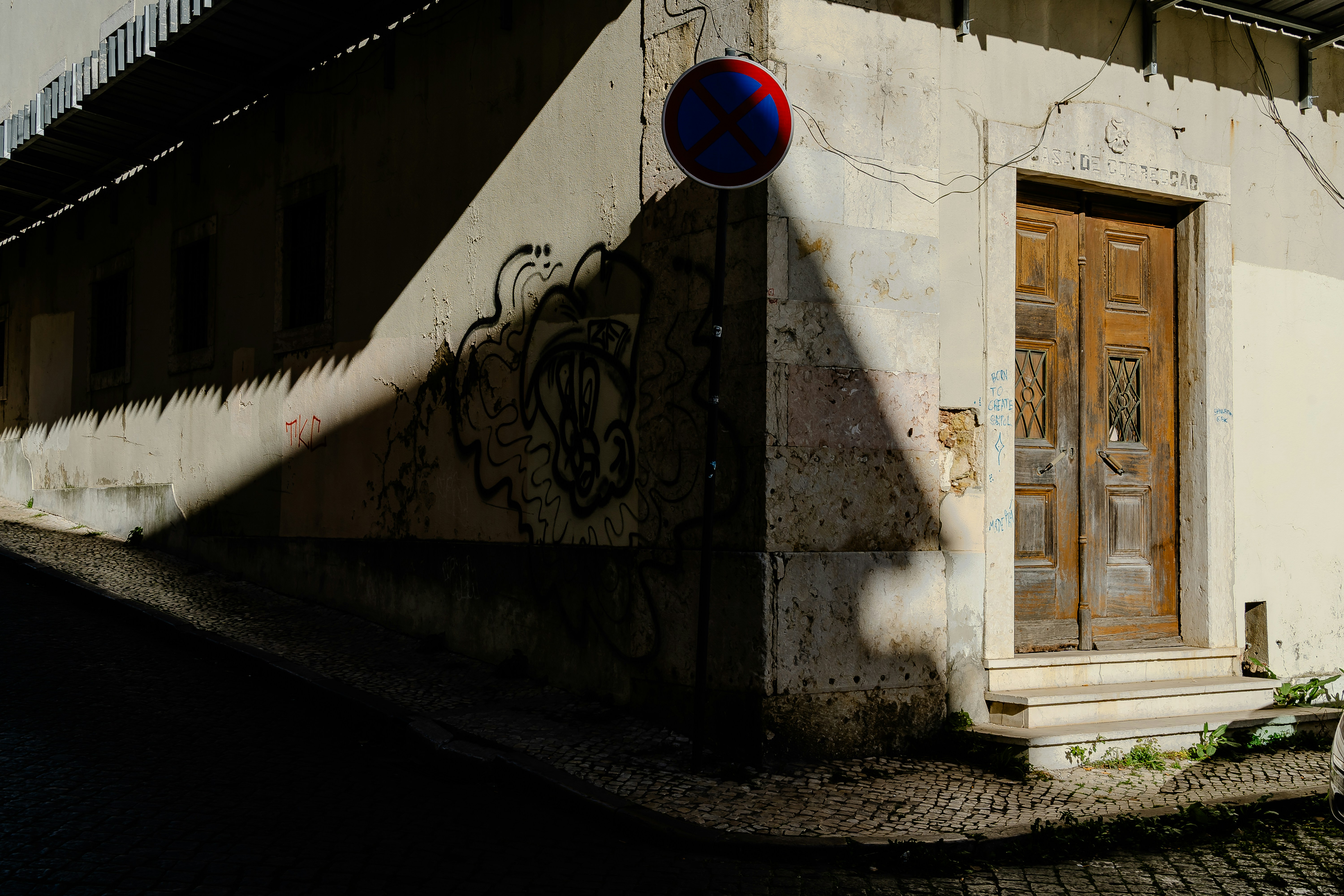 Corner of a building with a wooden door and graffiti.