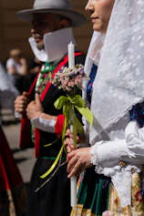 People in traditional costumes holding a candle