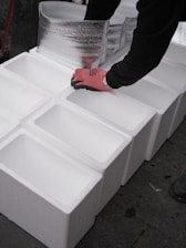 Hands arranging white styrofoam boxes in a line.