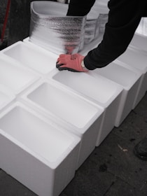 Hands arranging white styrofoam boxes in a line.