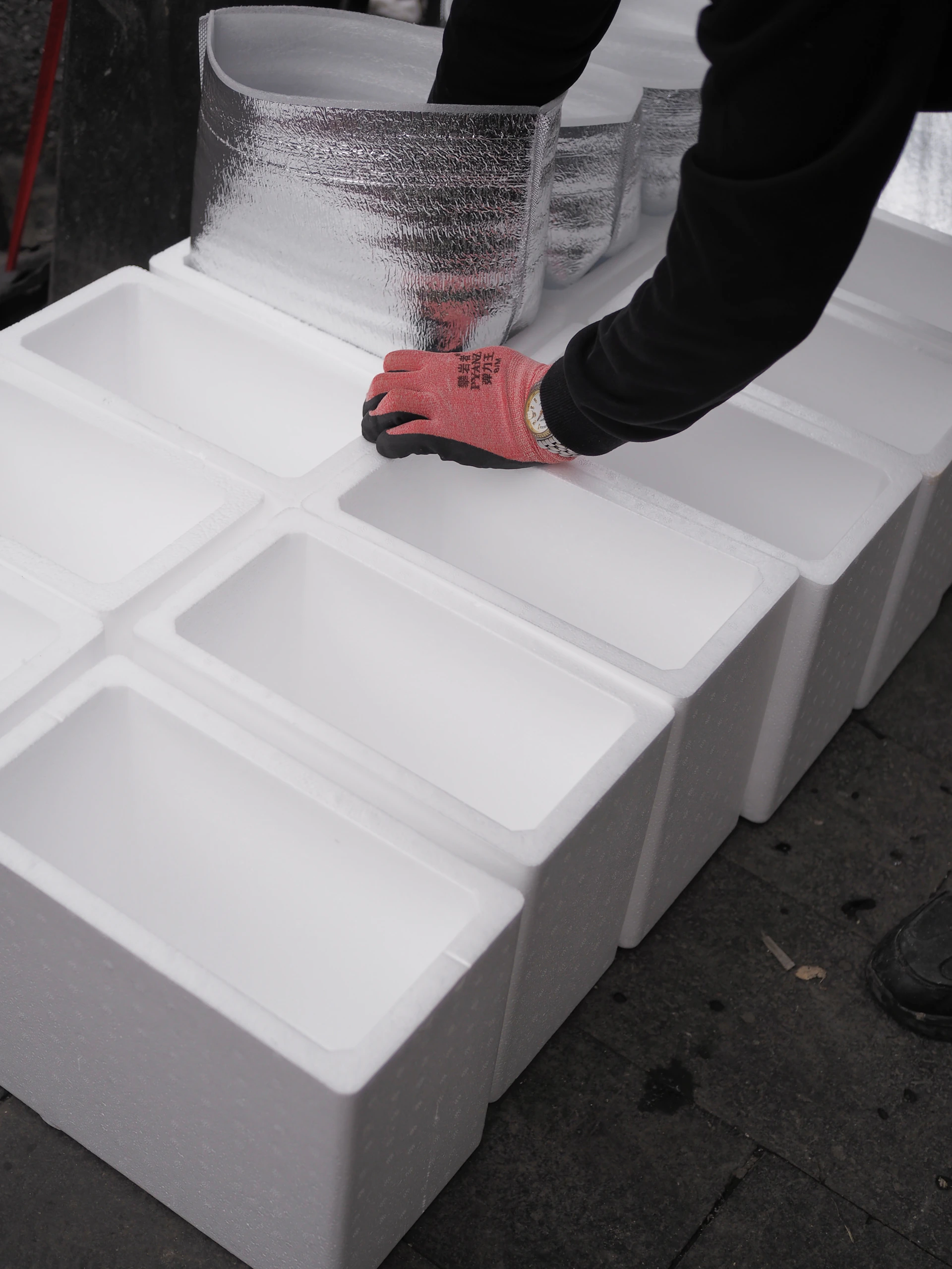 Hands arranging white styrofoam boxes in a line