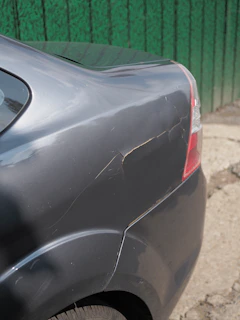Damaged grey car fender with cracked paint