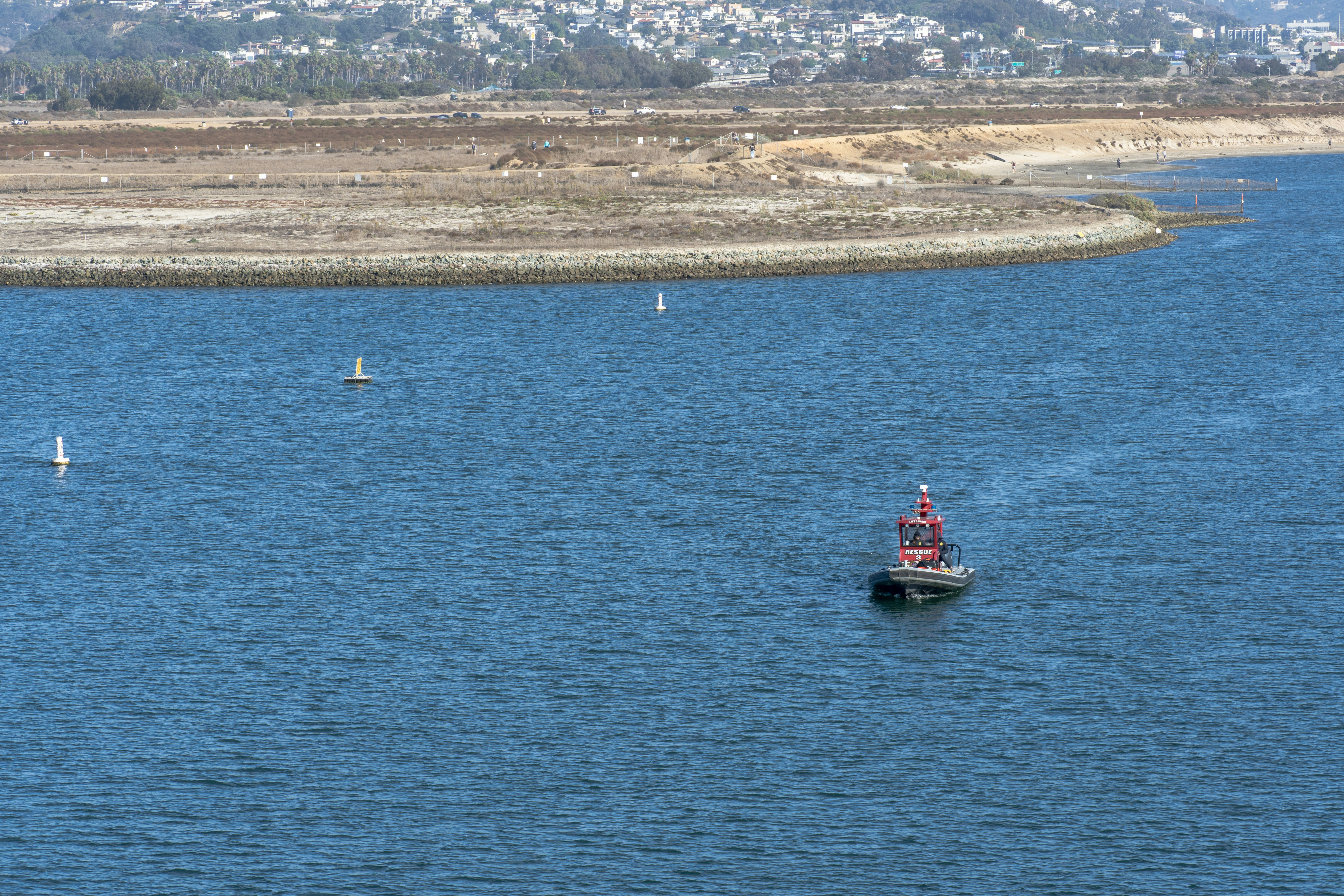 Red buoy floats on blue water near shore