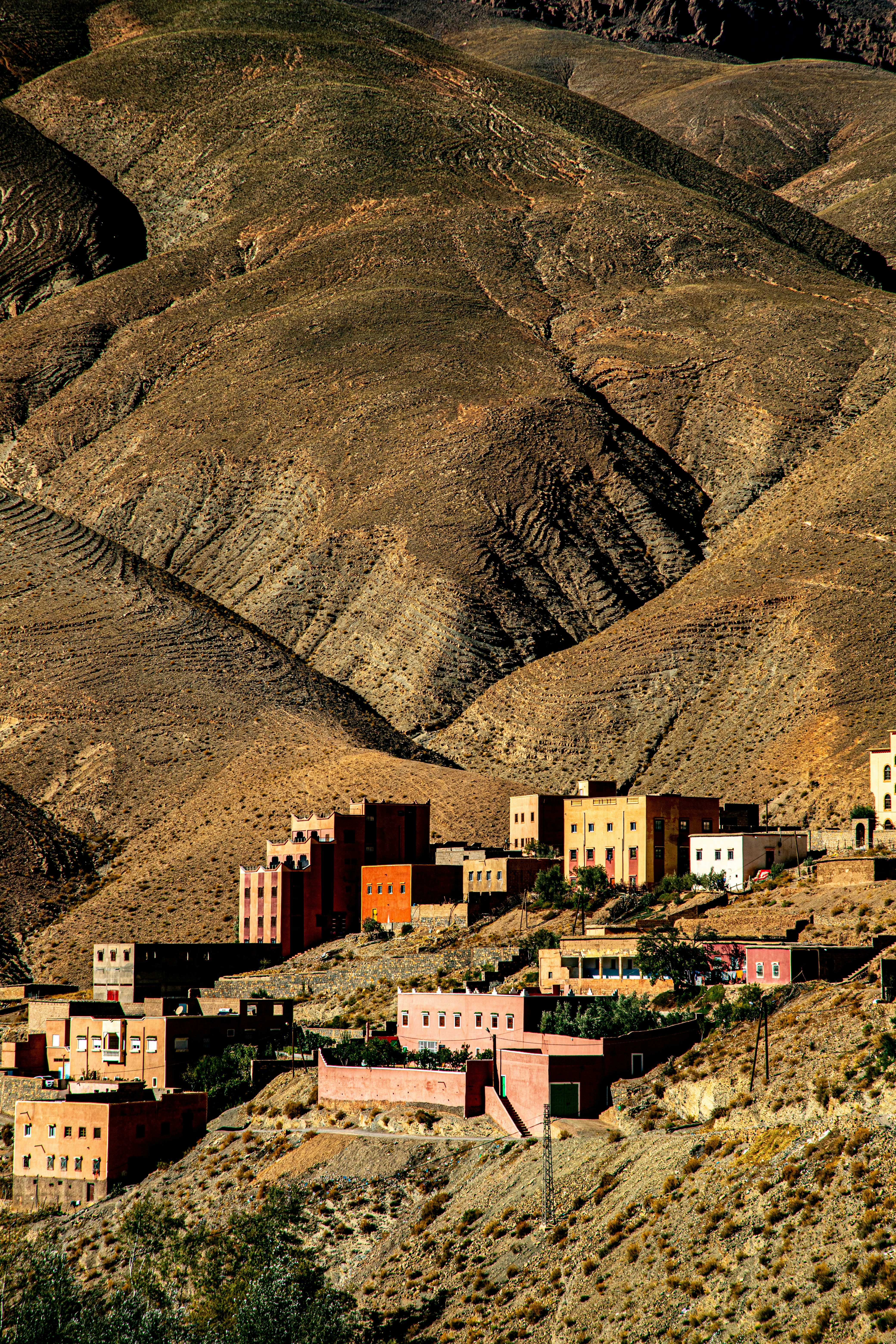Village nestled in arid, mountainous terrain at sunset.