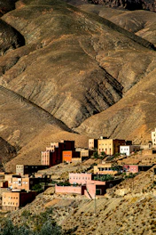 Village nestled in arid, mountainous terrain at sunset.