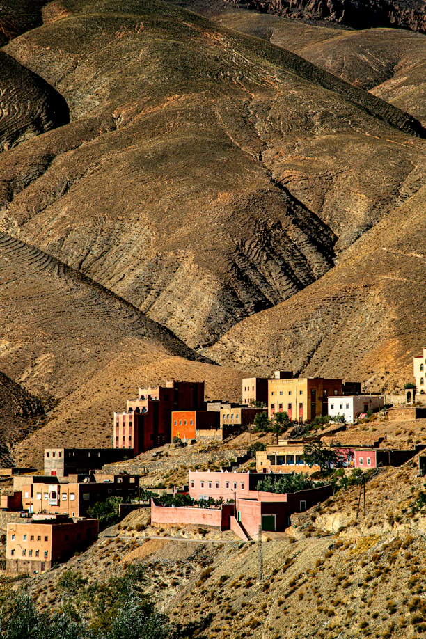 Village nestled in arid, mountainous terrain at sunset.