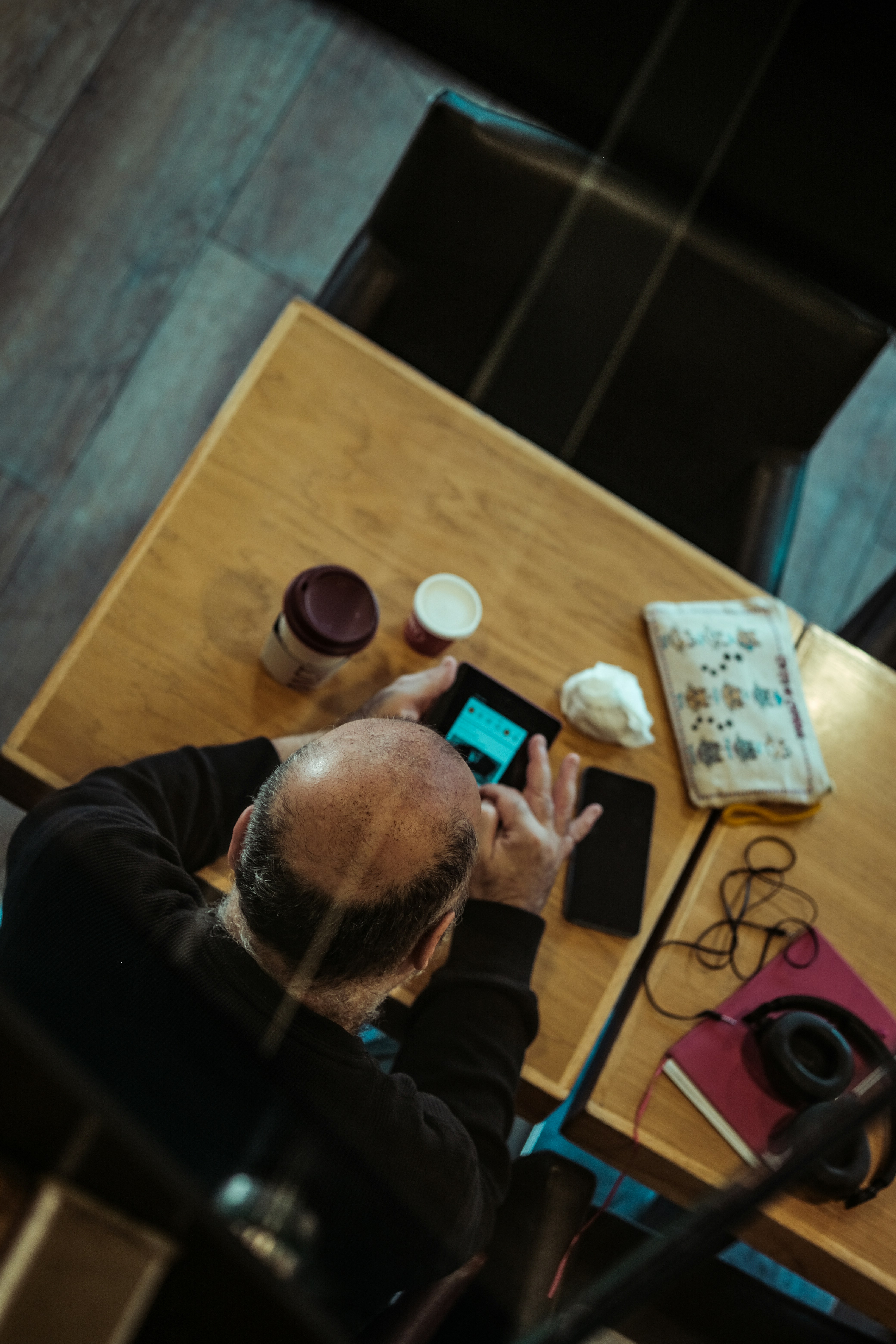 Man sitting at table with tablet and headphones.