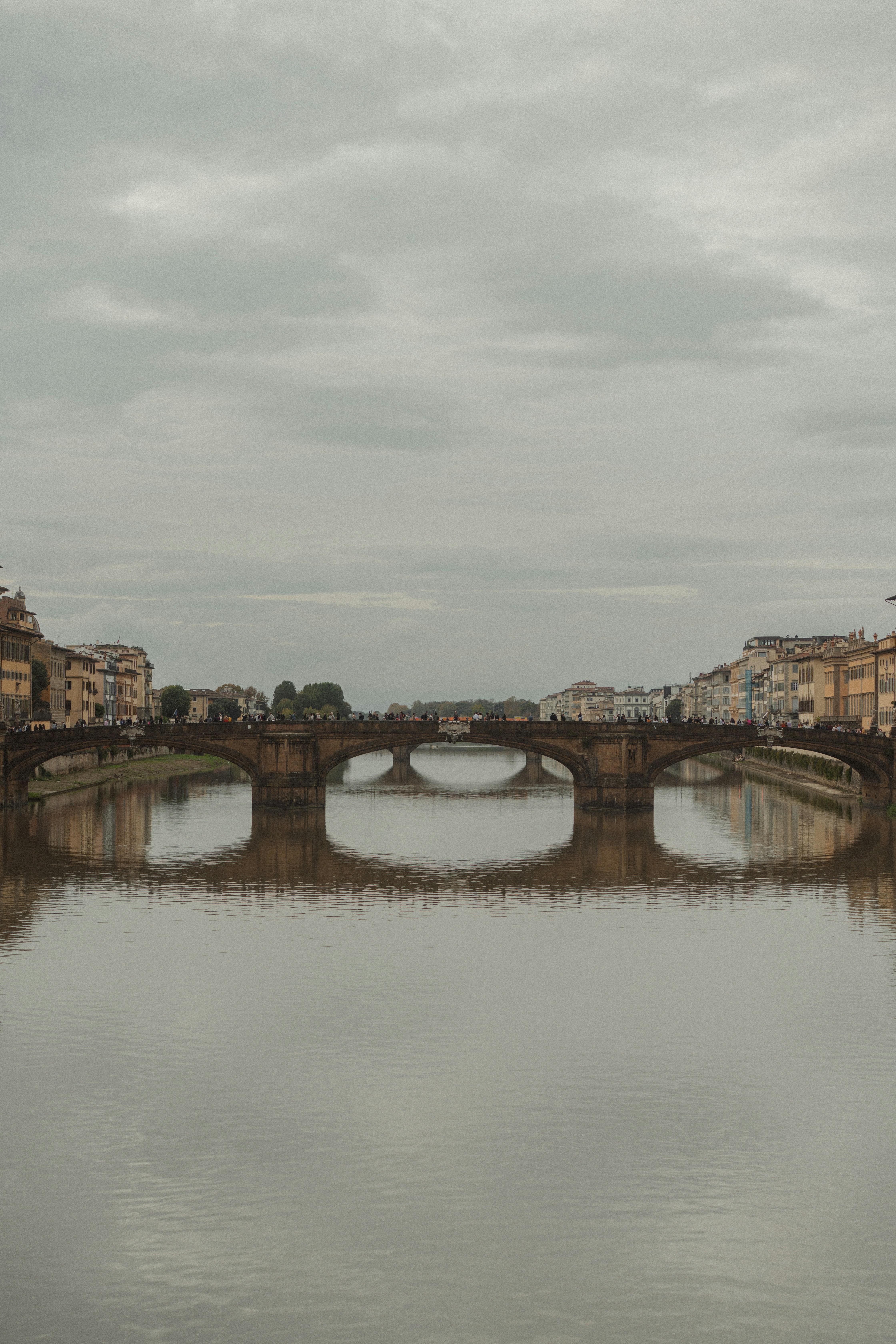 Ponte de pedra sobre um rio calmo com edifícios.