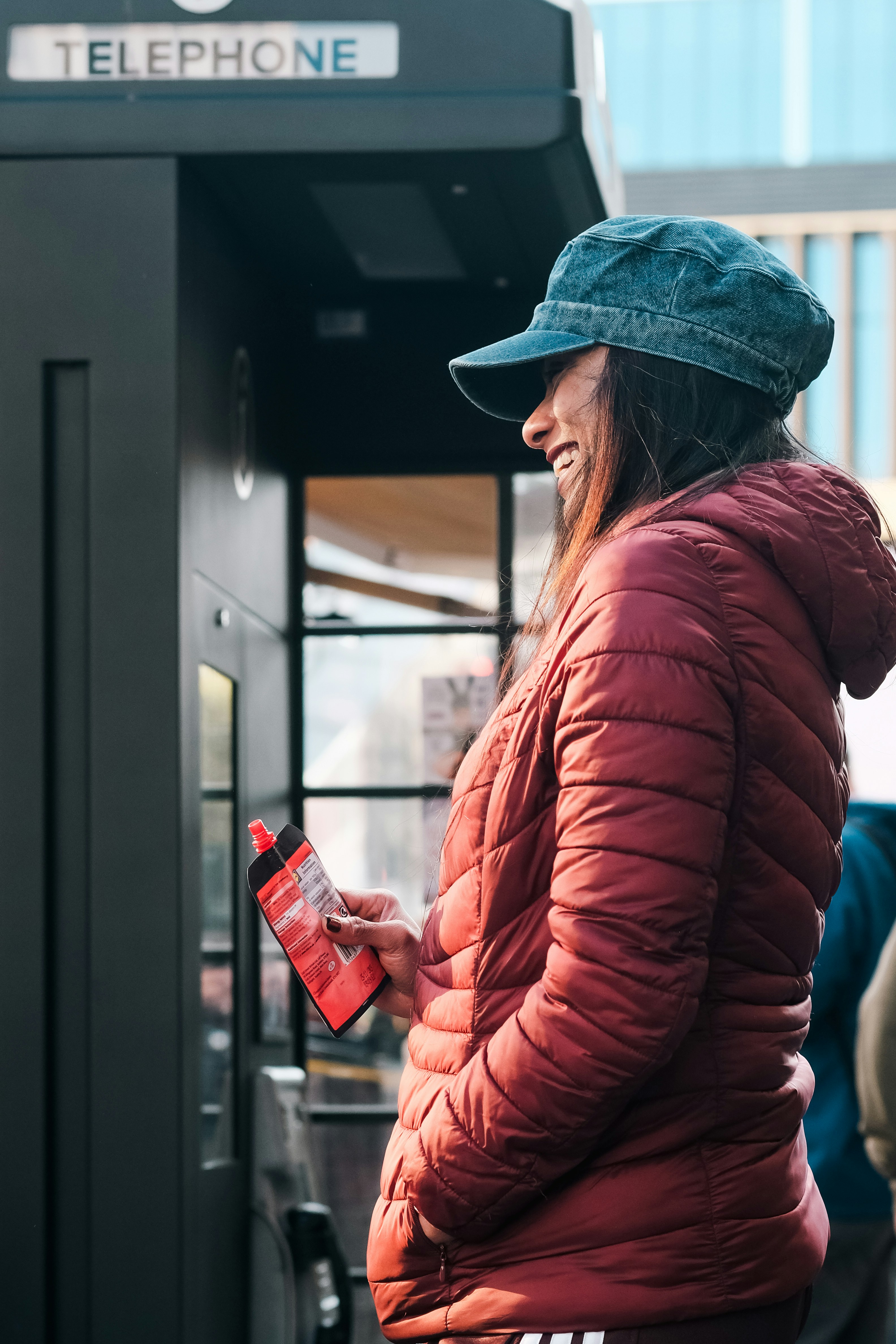 Woman in red jacket using a public telephone booth