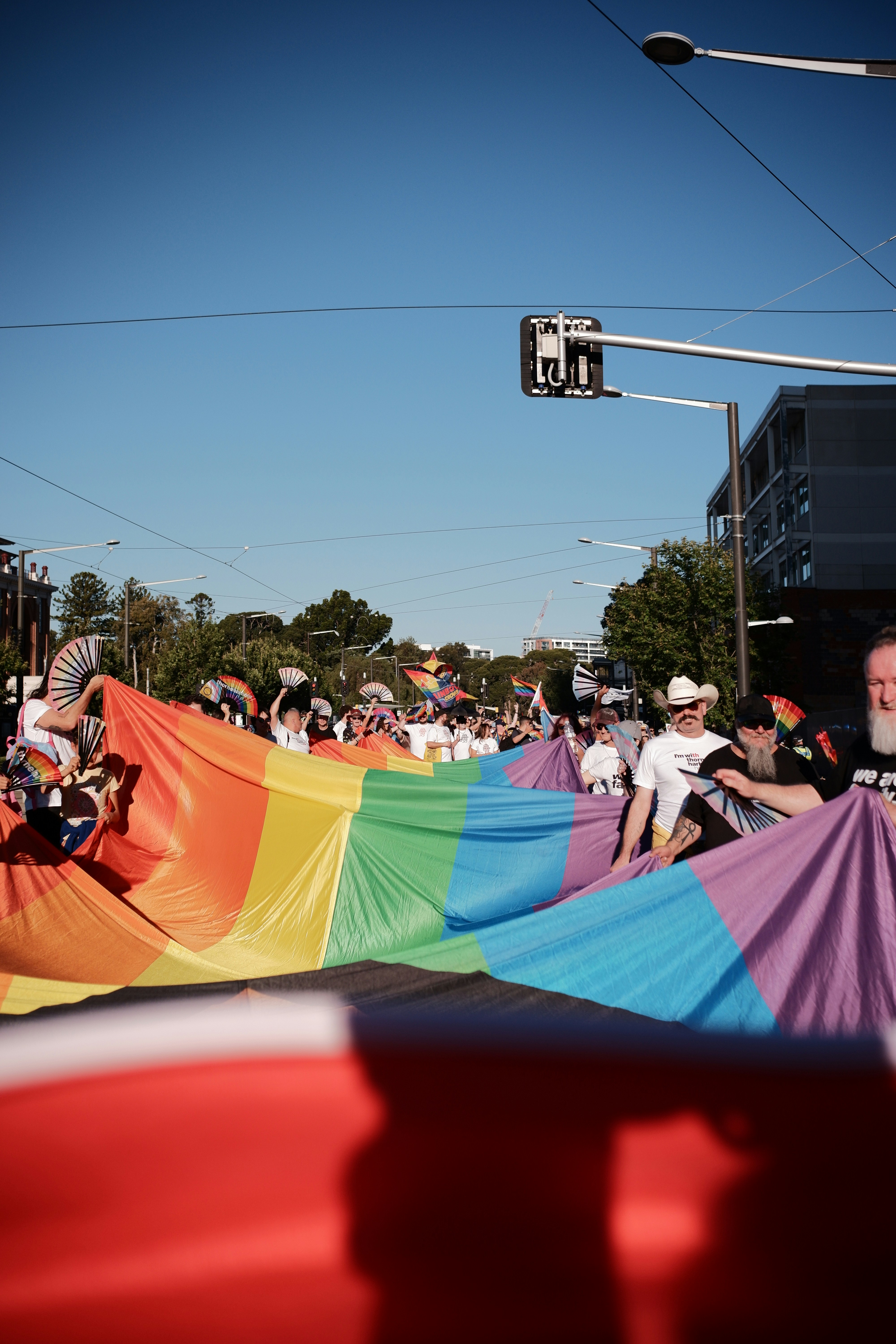 People holding a large rainbow flag at a parade.