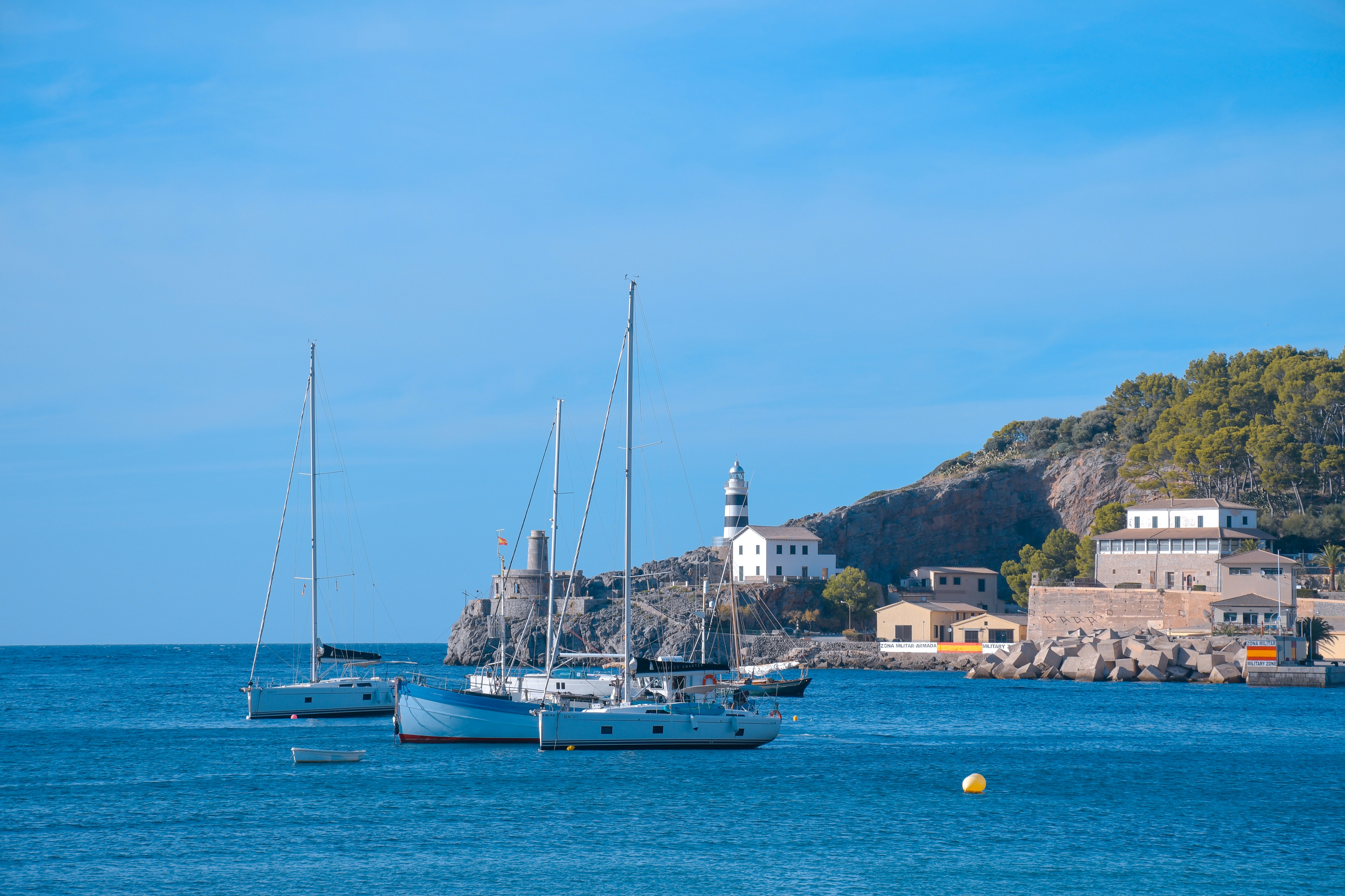 Sailboats on the water near a coastal village.