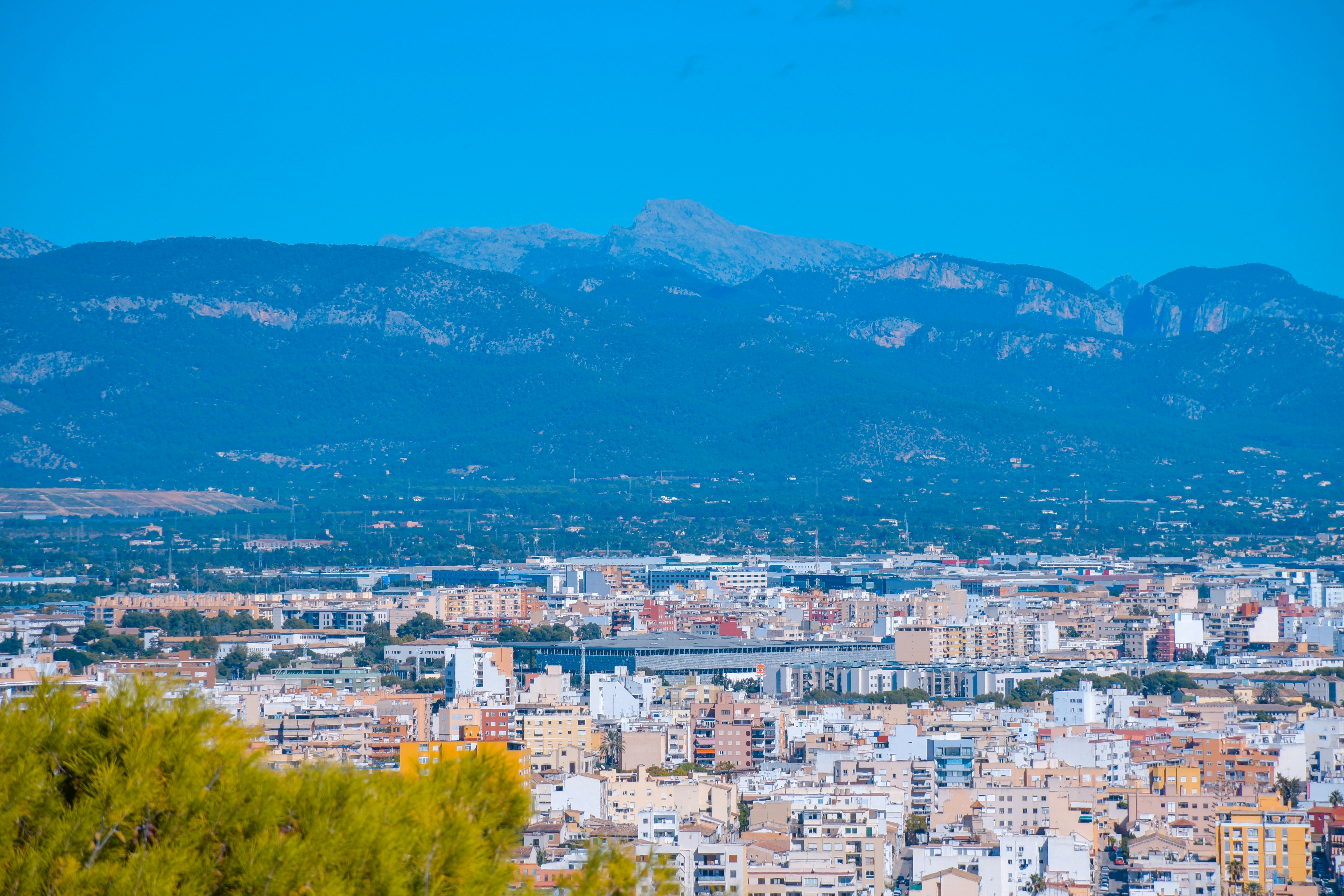 Cityscape with mountains in the background under blue sky.