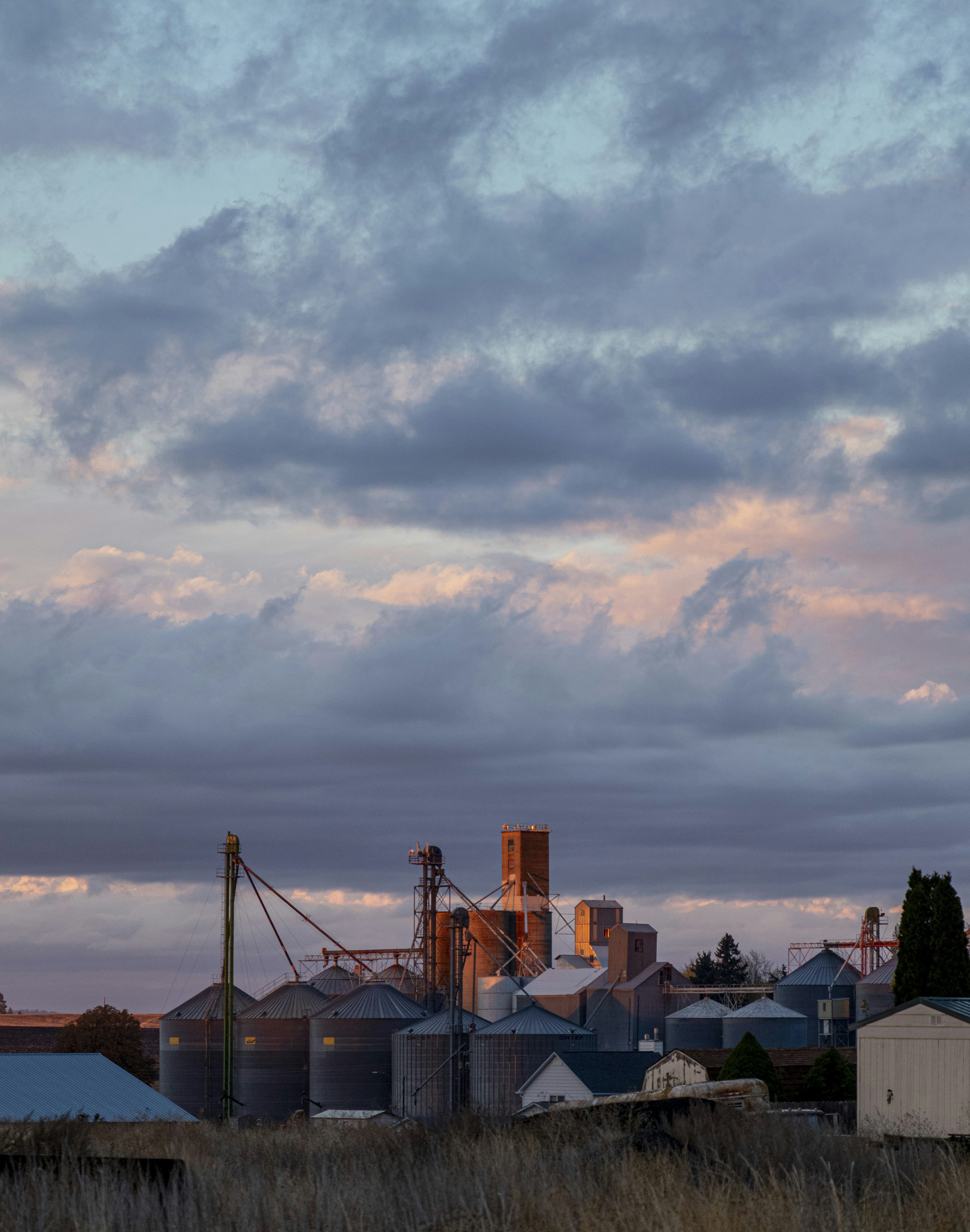 Industrial grain silos at sunset with dramatic clouds