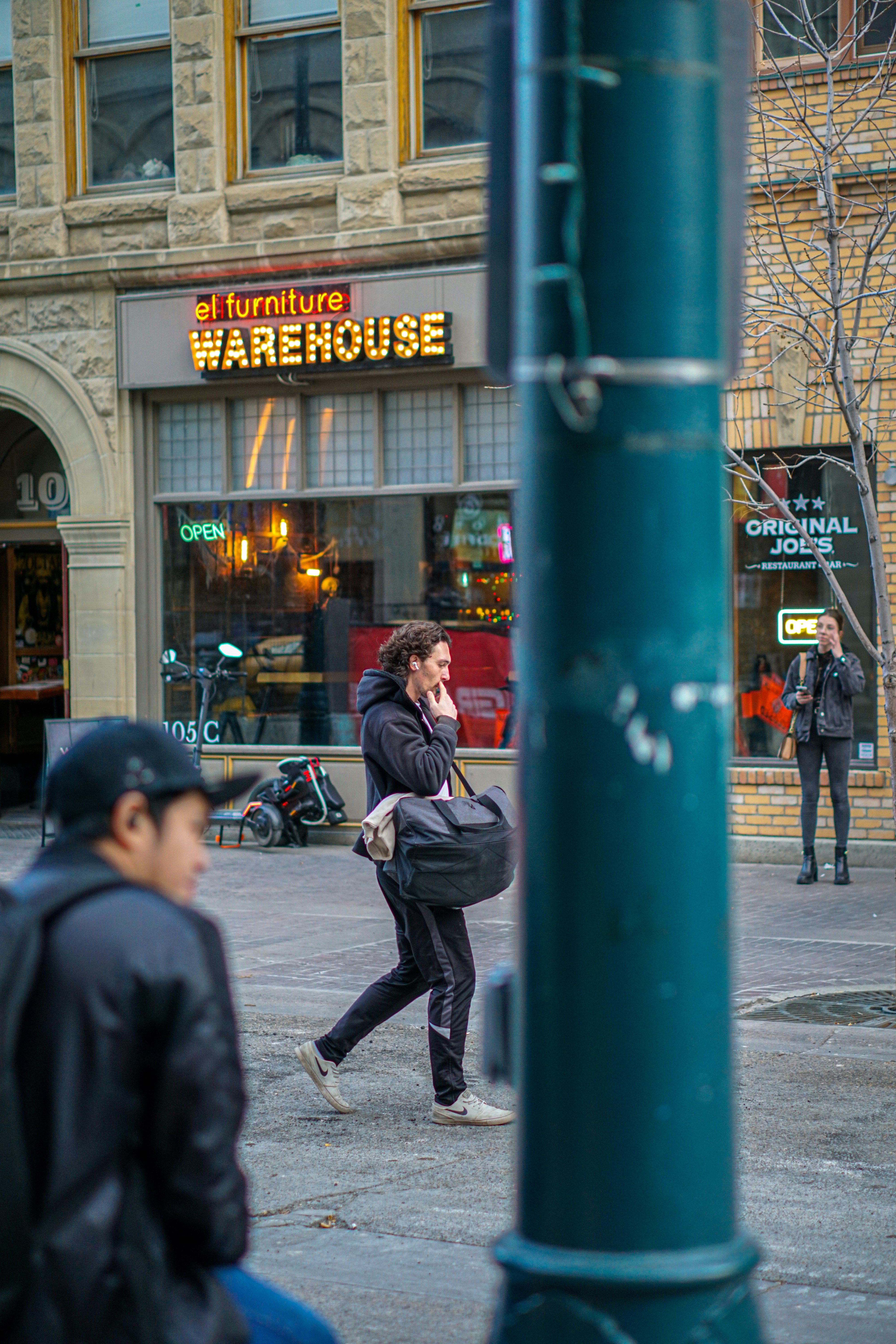 Man walking on city street past storefronts.