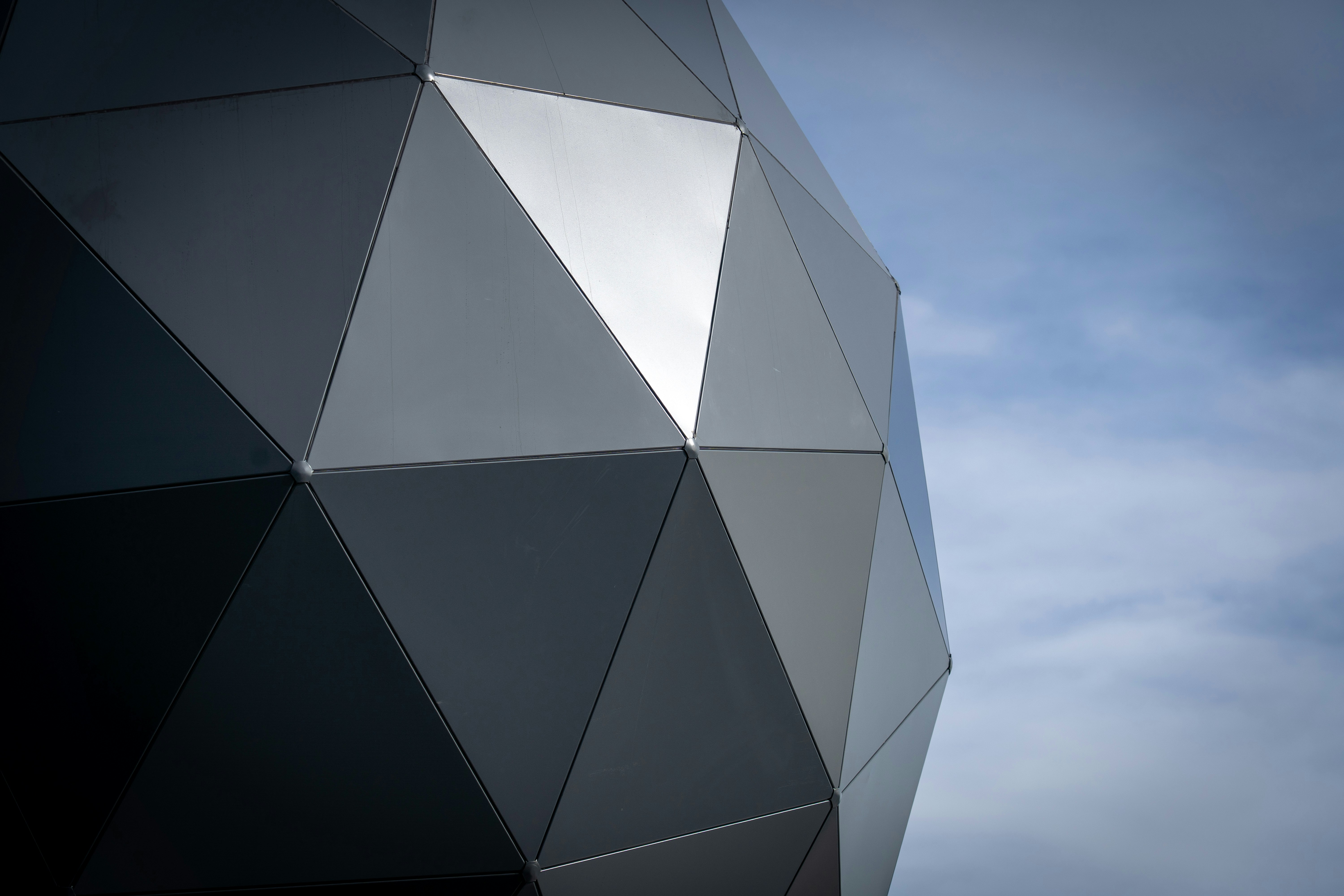 Geometric dome structure against a cloudy sky.