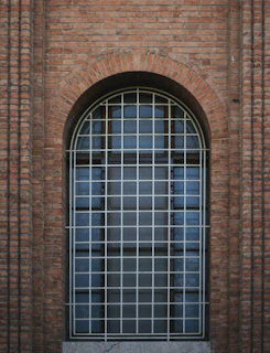 Arched window with white bars on brick wall