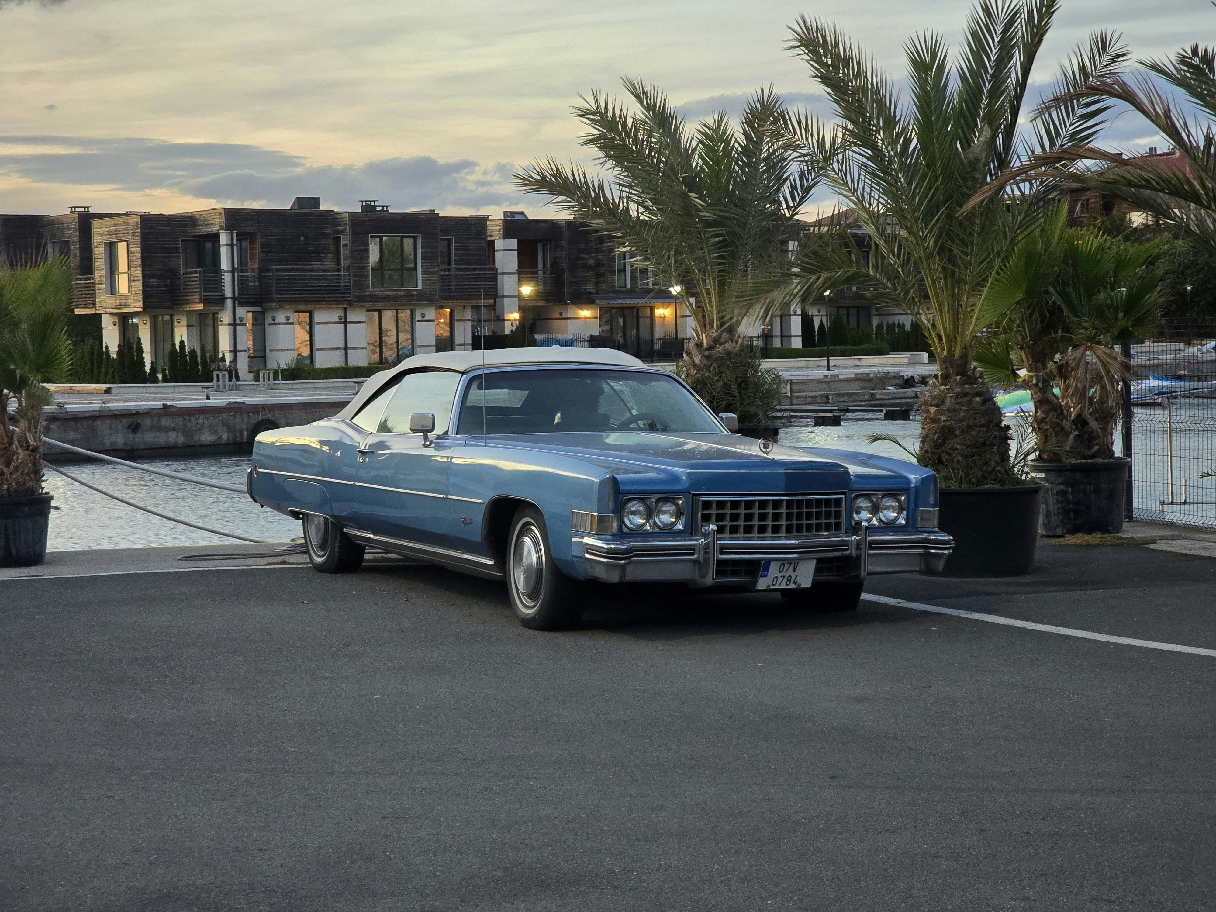 A classic blue cadillac parked by the water