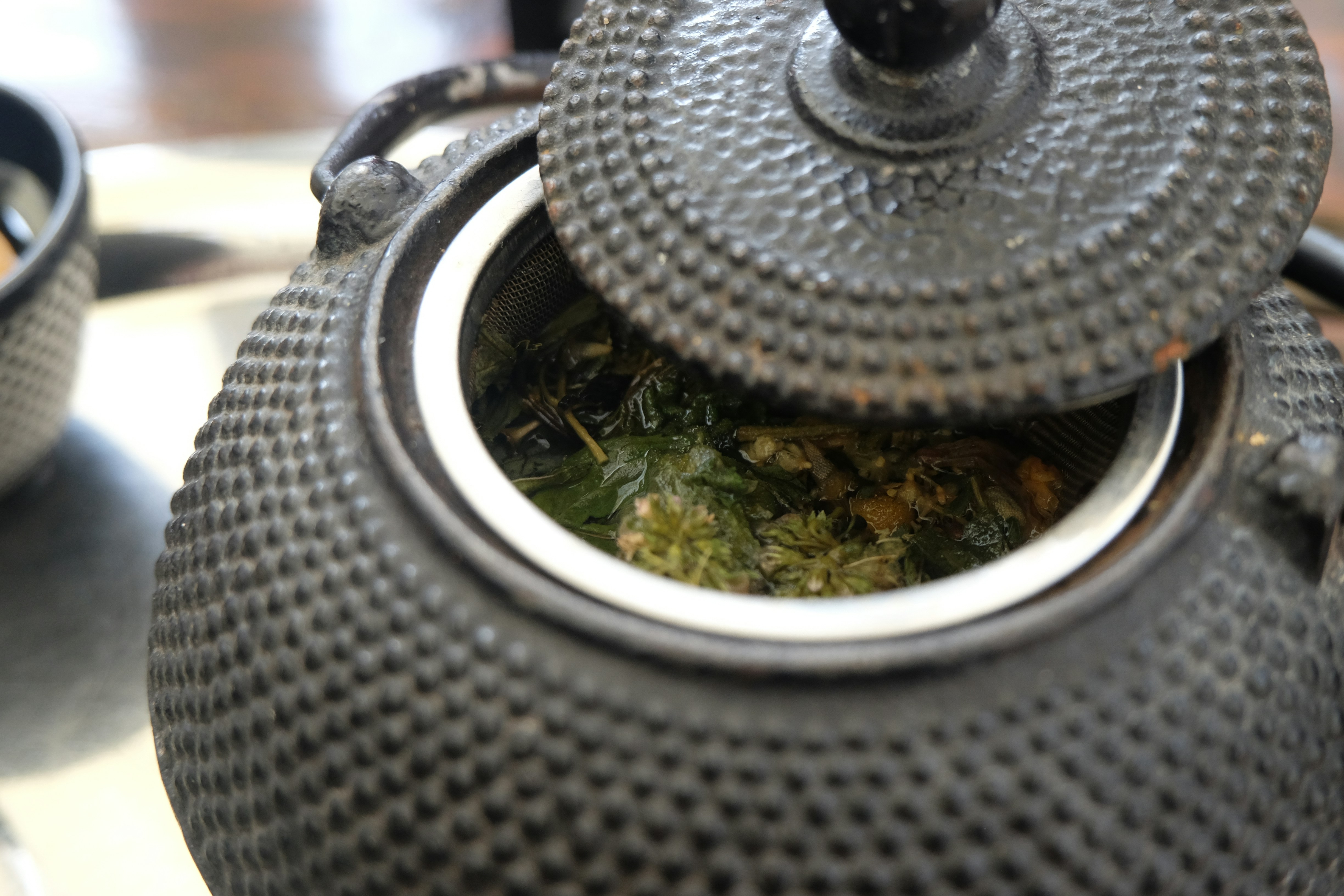 Close-up of a cast iron teapot with loose leaf tea.