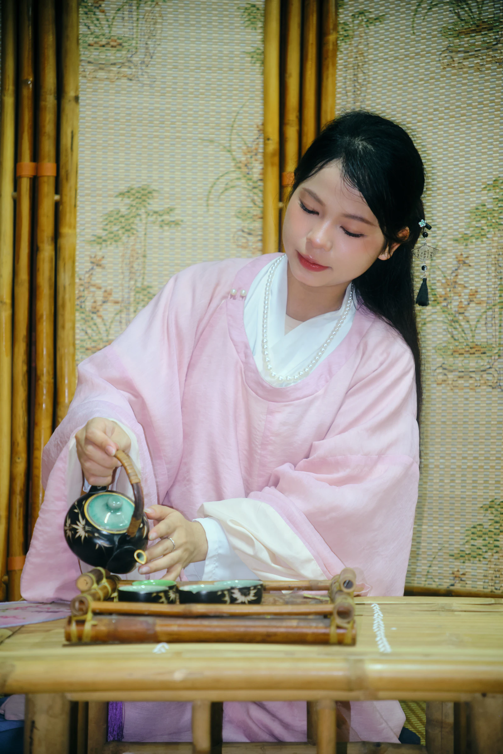 A woman in a pink traditional dress pouring tea at a tasting table