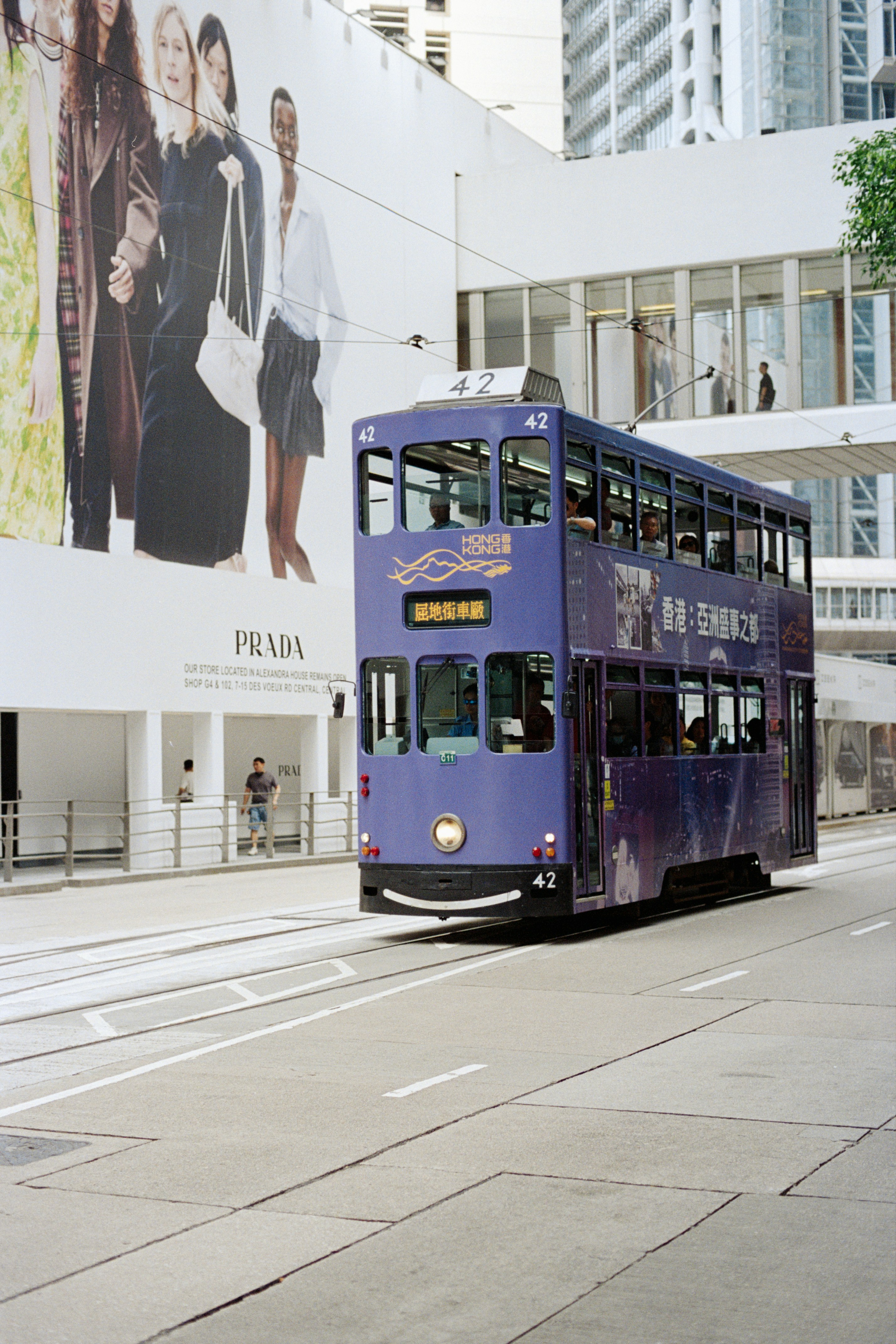 A purple double-decker tram drives down a city street.