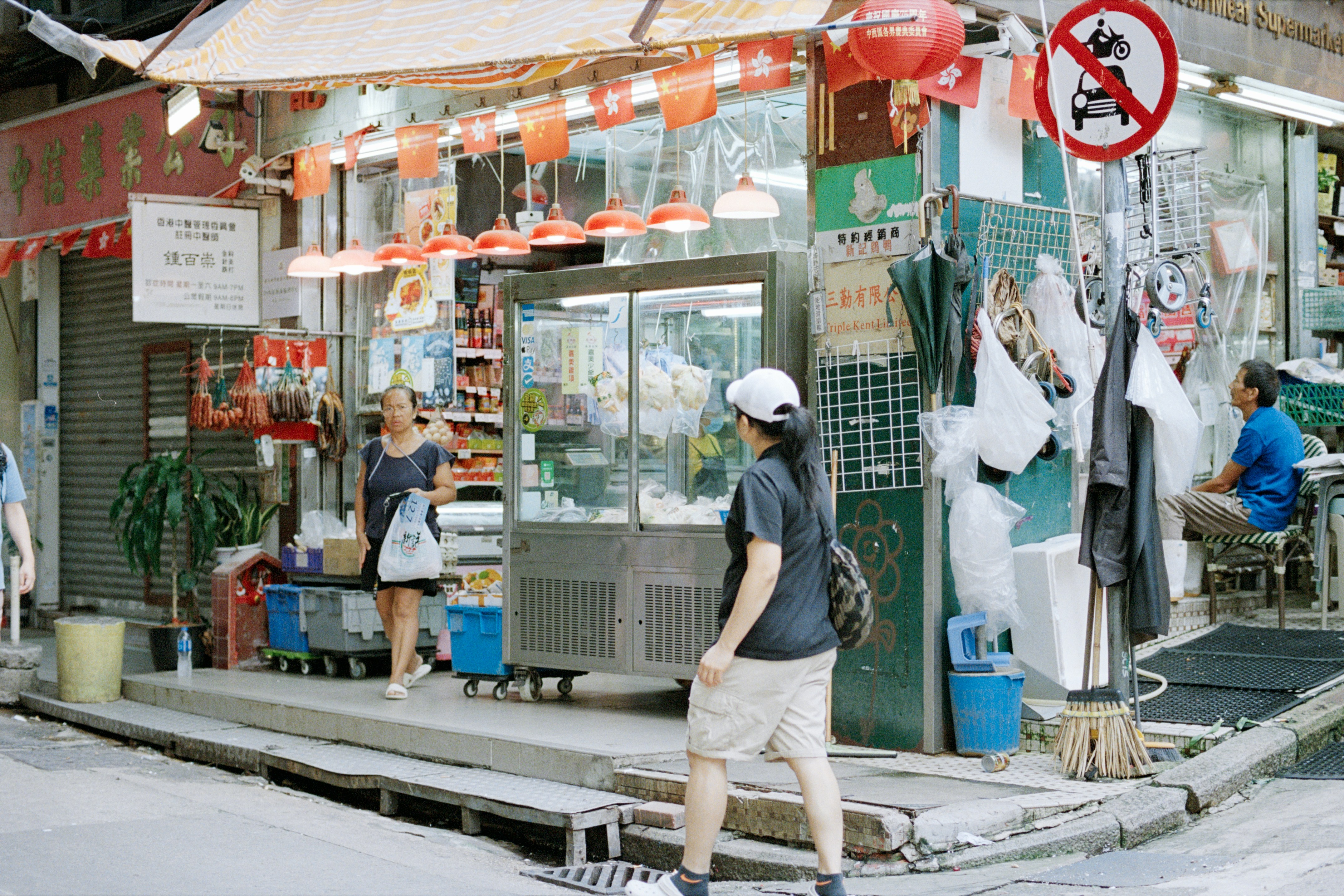 Street corner with a small independent shop and people walking past