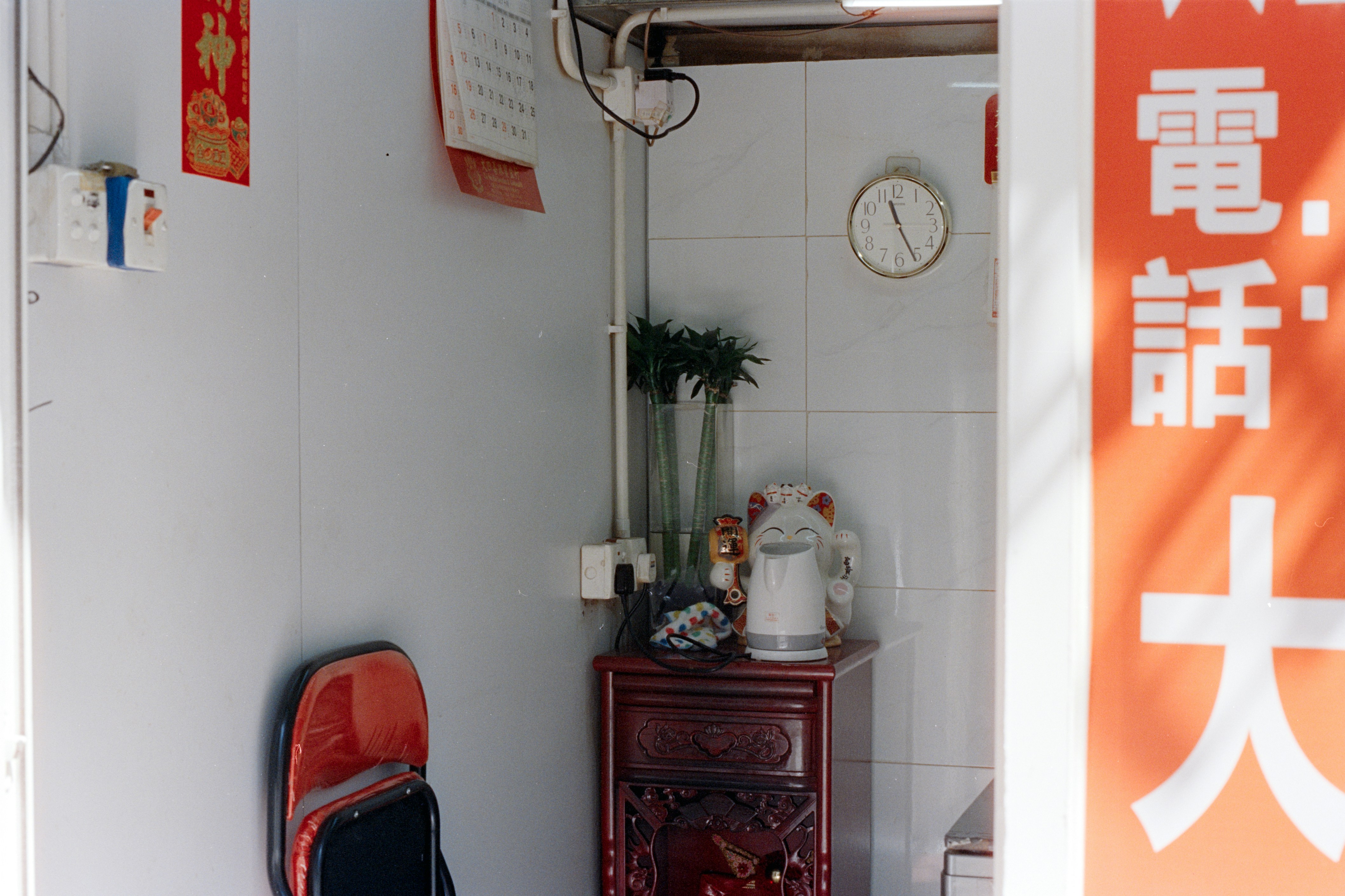 Corner of a room with a red chair and cabinet.