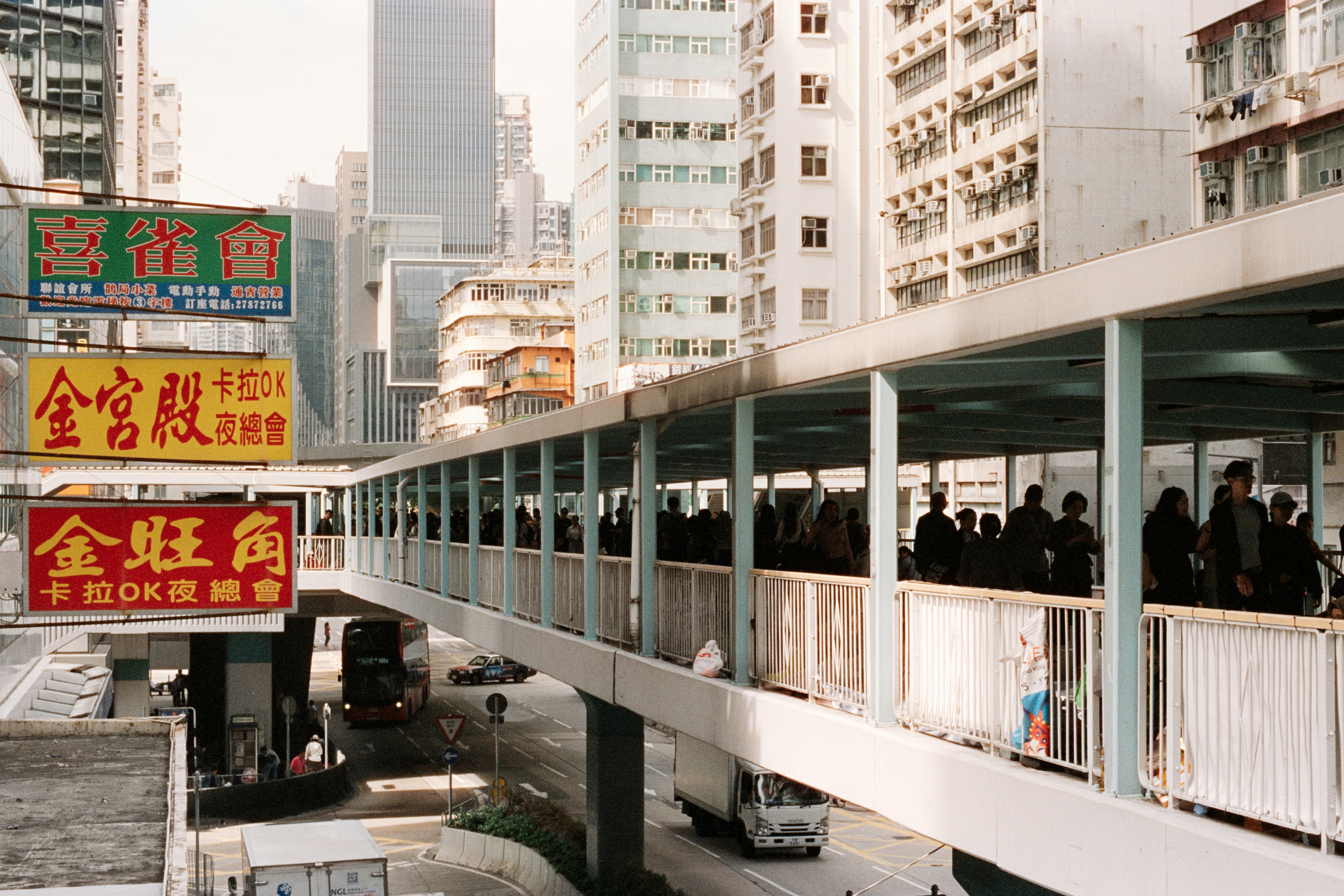People walk on an elevated walkway in a city.