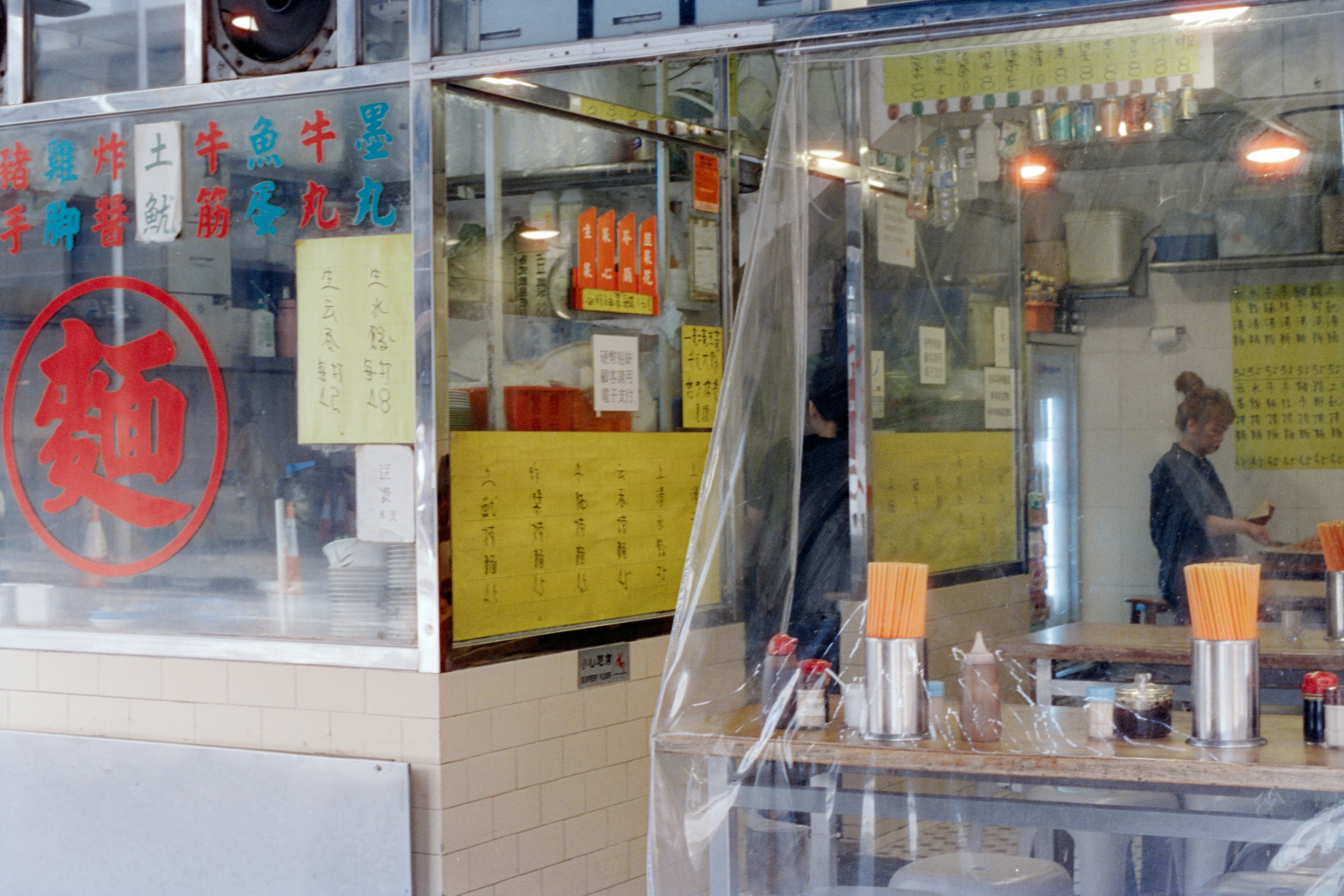 A woman works in a small restaurant with yellow menus.