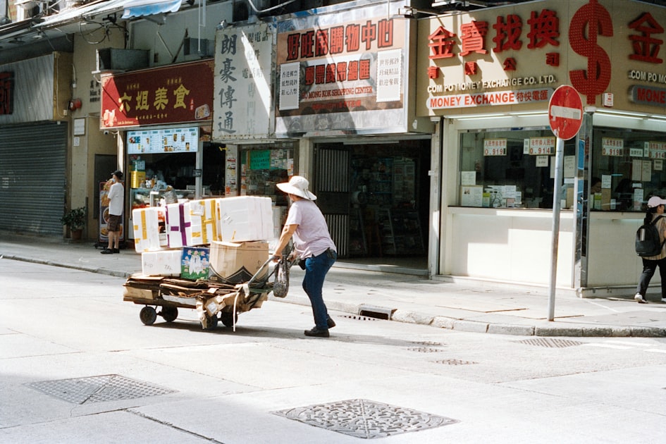 Person pushing cart with boxes on street.