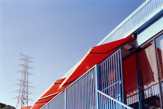 Red awnings on a building with a power tower.