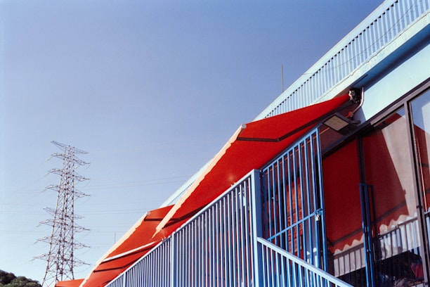 Red awnings on a building with a power tower.