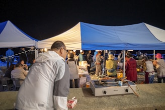 People gathered under tents at an outdoor night market.