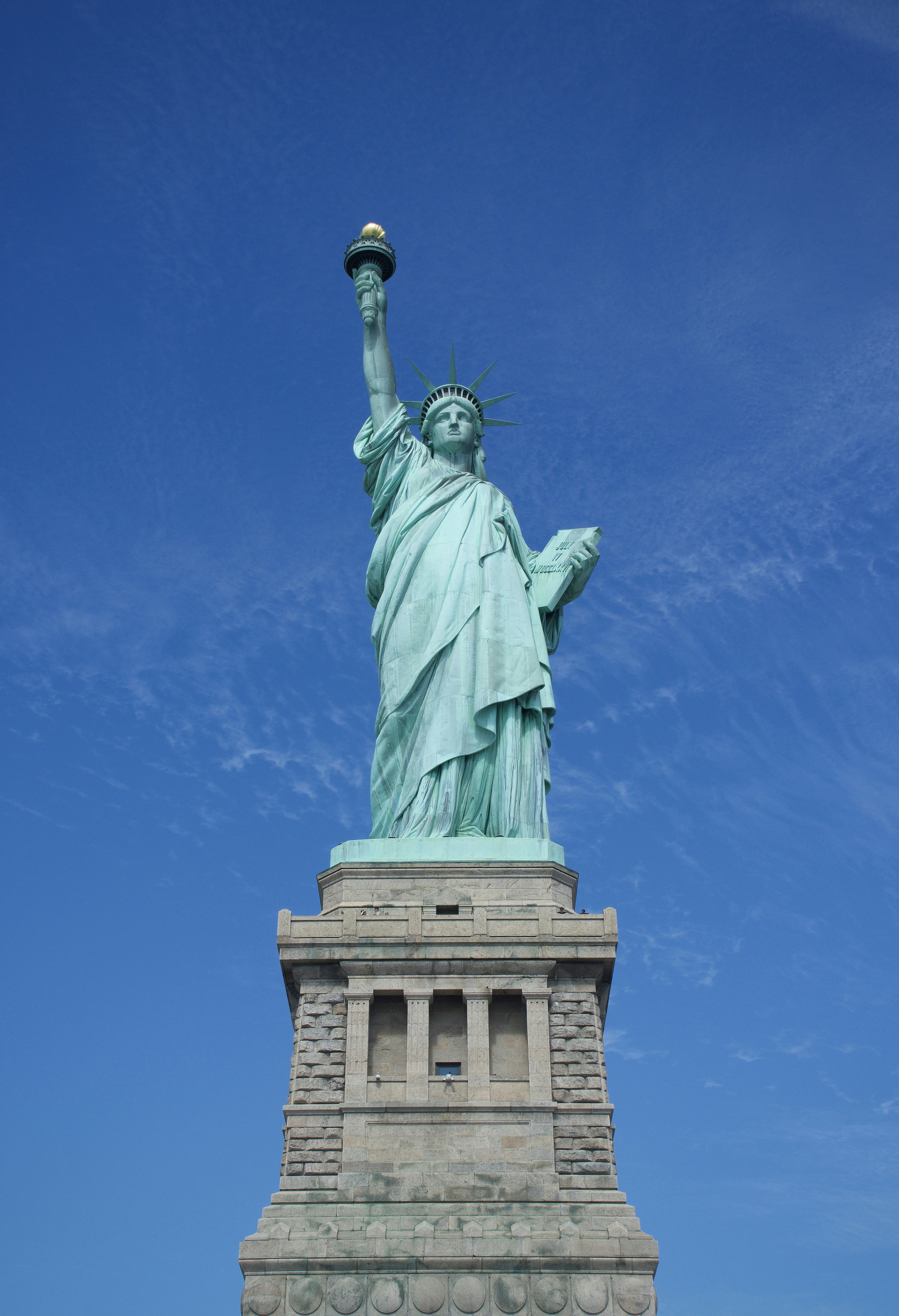 Die Freiheitsstatue steht vor blauem Himmel.