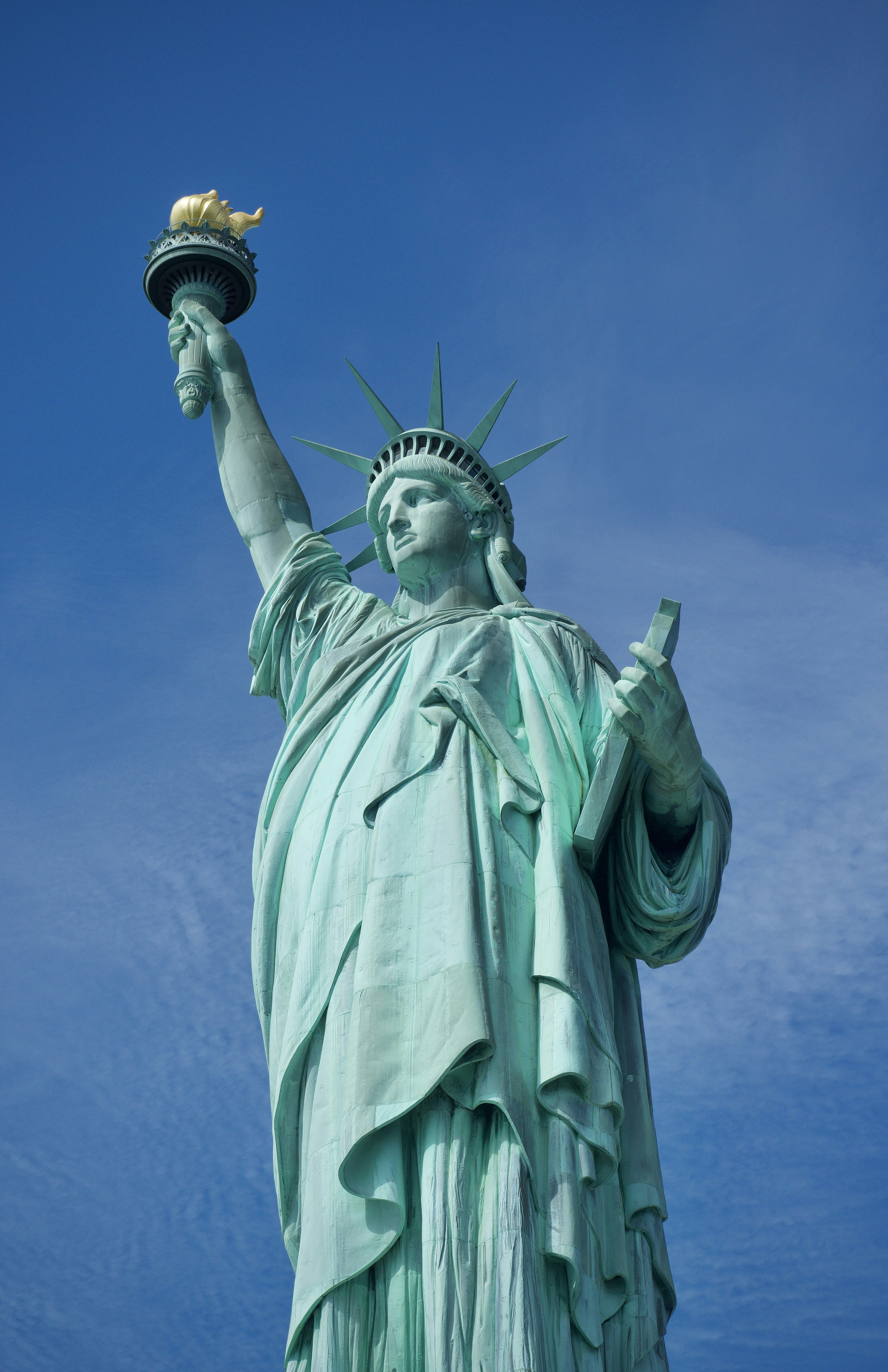 Die Freiheitsstatue steht vor strahlend blauem Himmel.