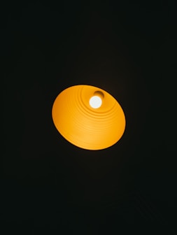 A bright orange lamp shade against a dark background.