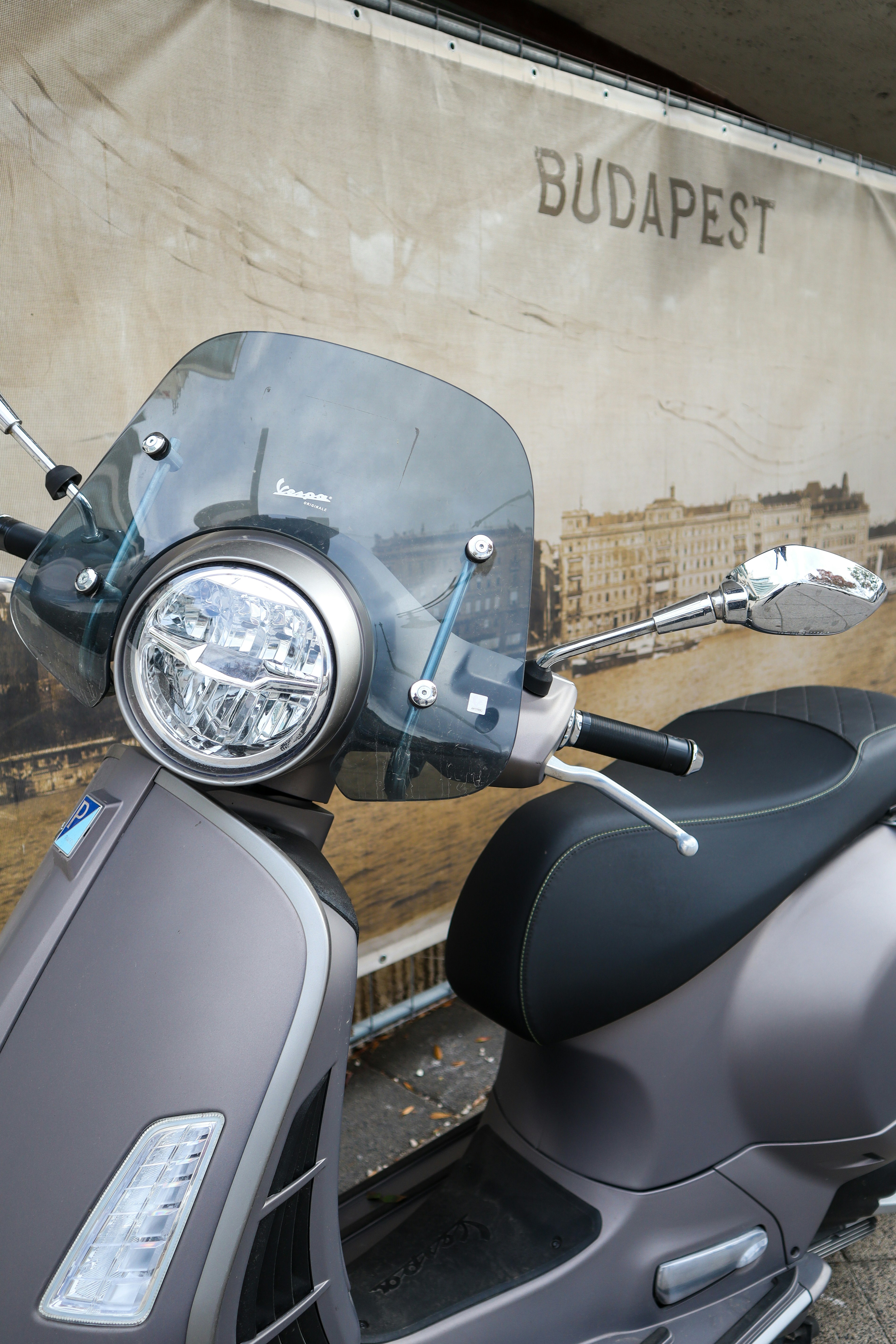 Grey scooter parked in front of budapest backdrop.